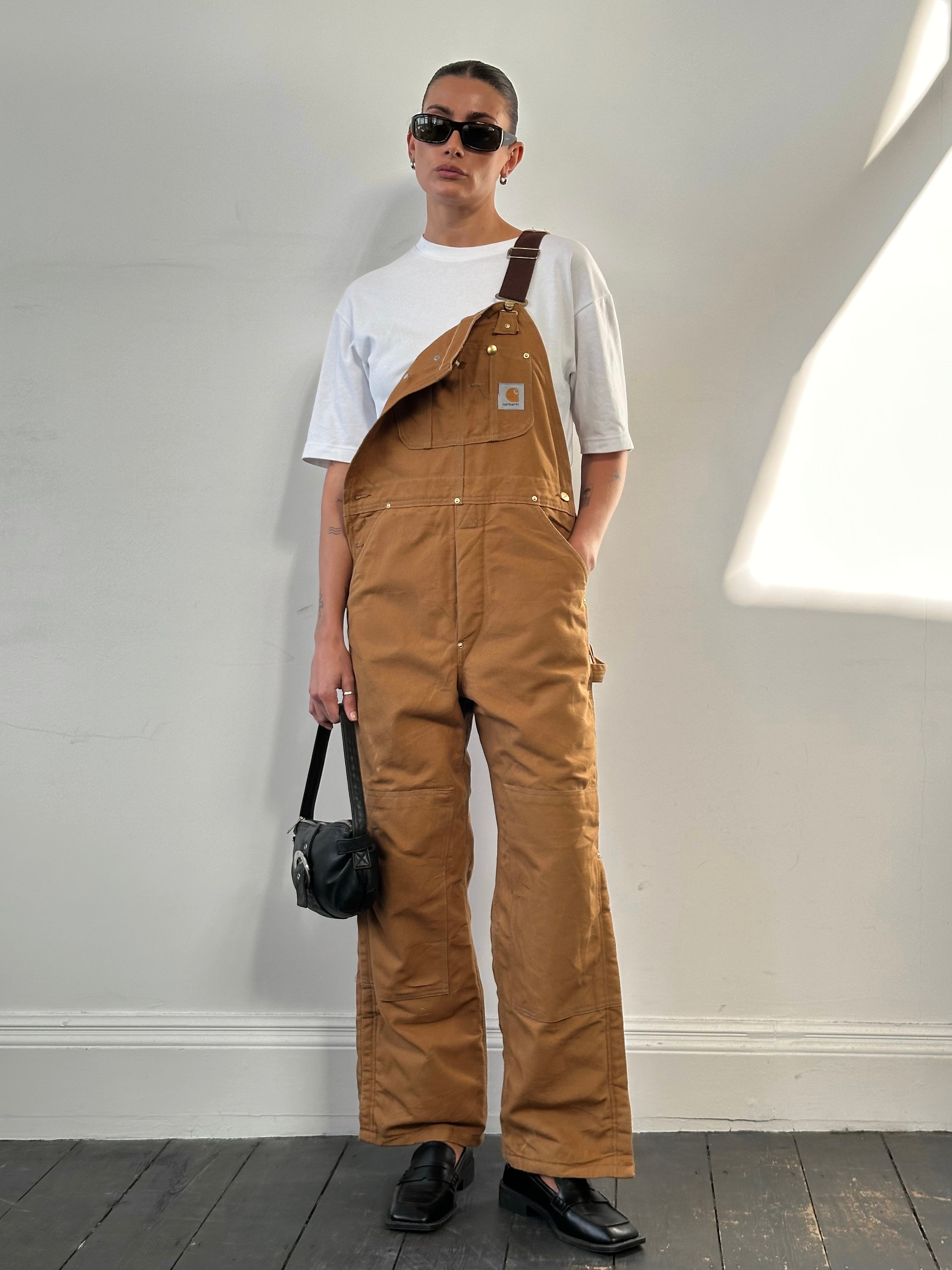 Carhartt pure cotton dungarees in size M, featuring durable fabric and classic workwear design, shown on a model.