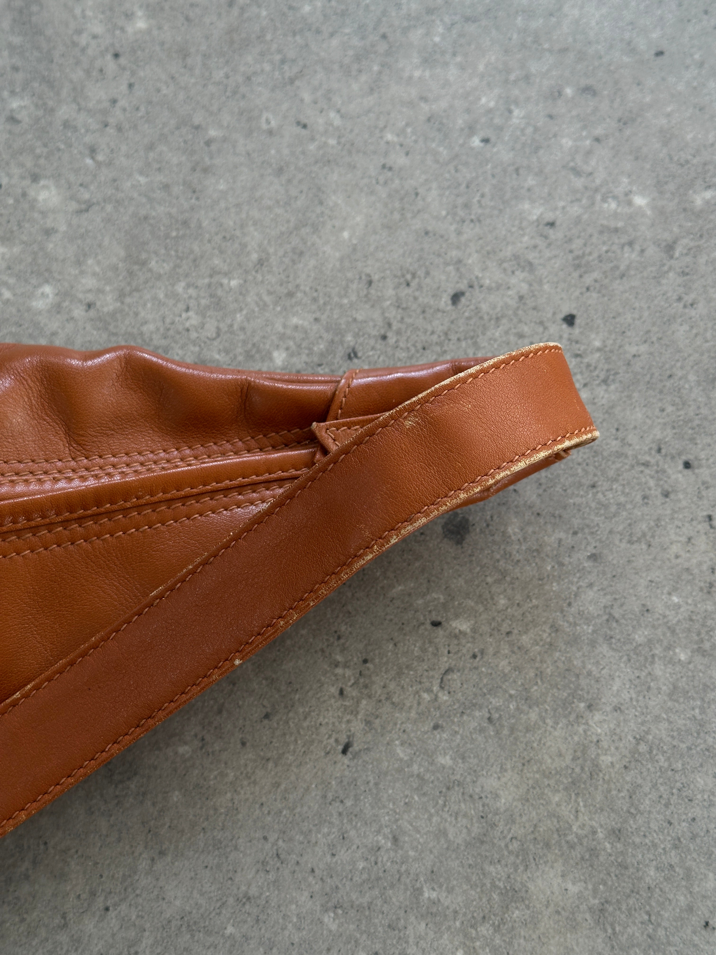 Yves Saint Laurent Paris 80s leather sling bag with adjustable strap and classic YSL logo detail on black leather.
