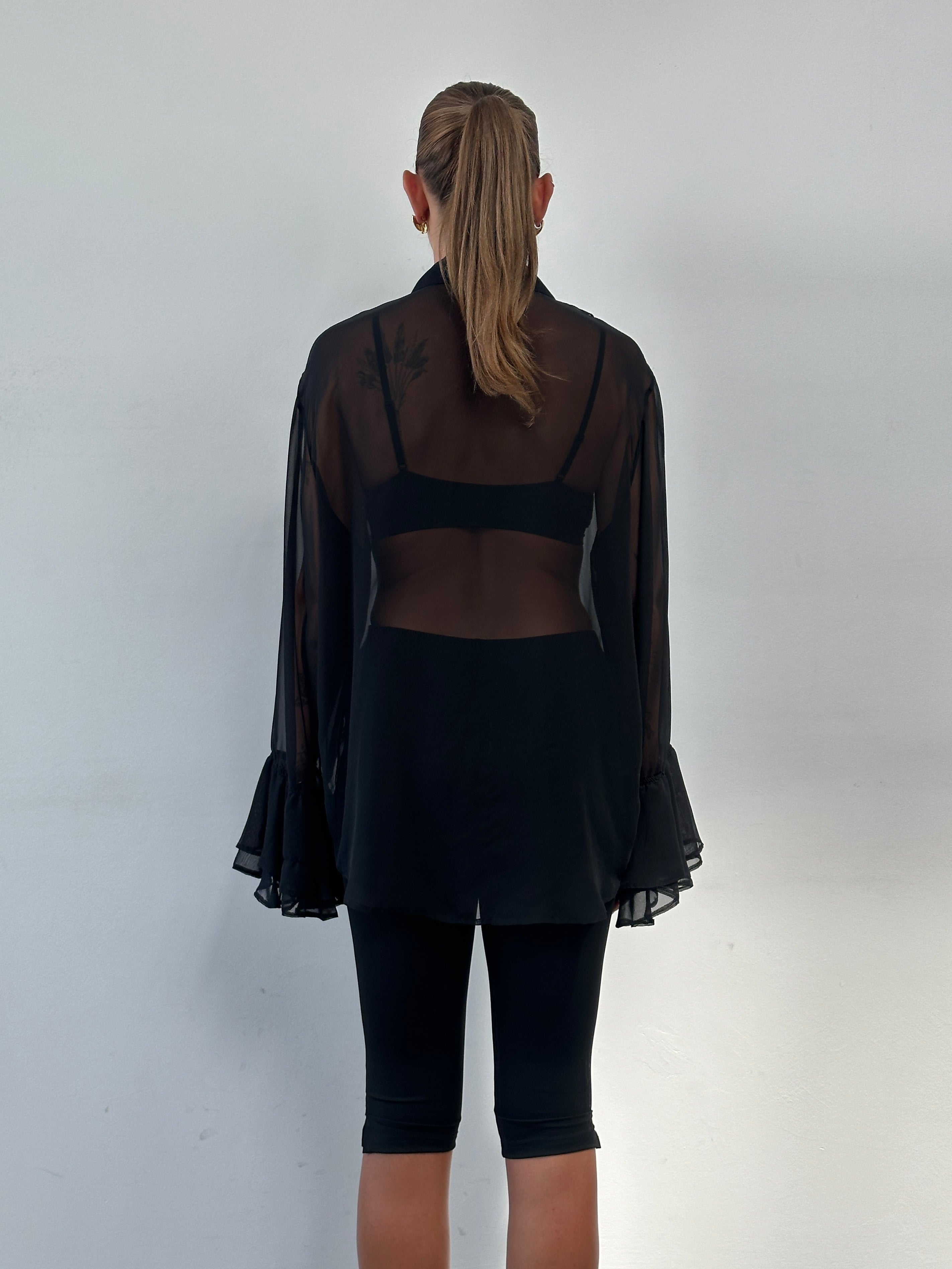 Vintage 2000s sheer ruffle shirt in size L/XL, featuring delicate ruffle details and lightweight fabric, styled for a vintage look.