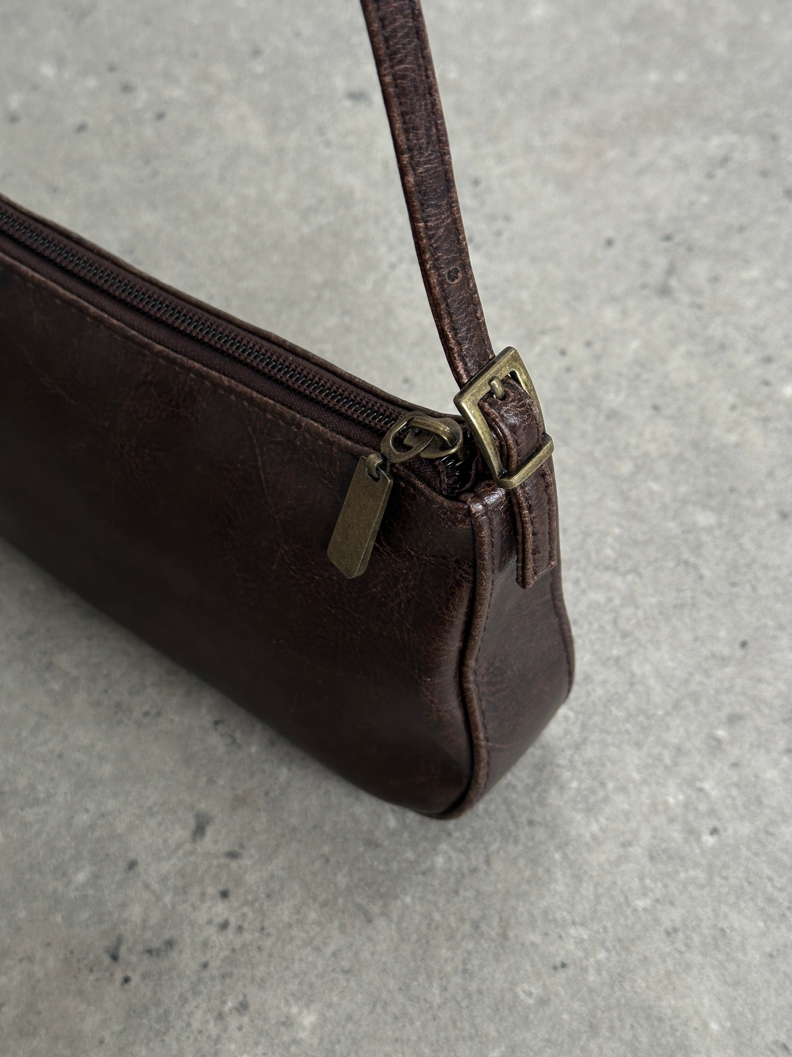 Vintage faux leather shoulder bag with adjustable strap and classic design, showcasing its textured surface and compact size.
