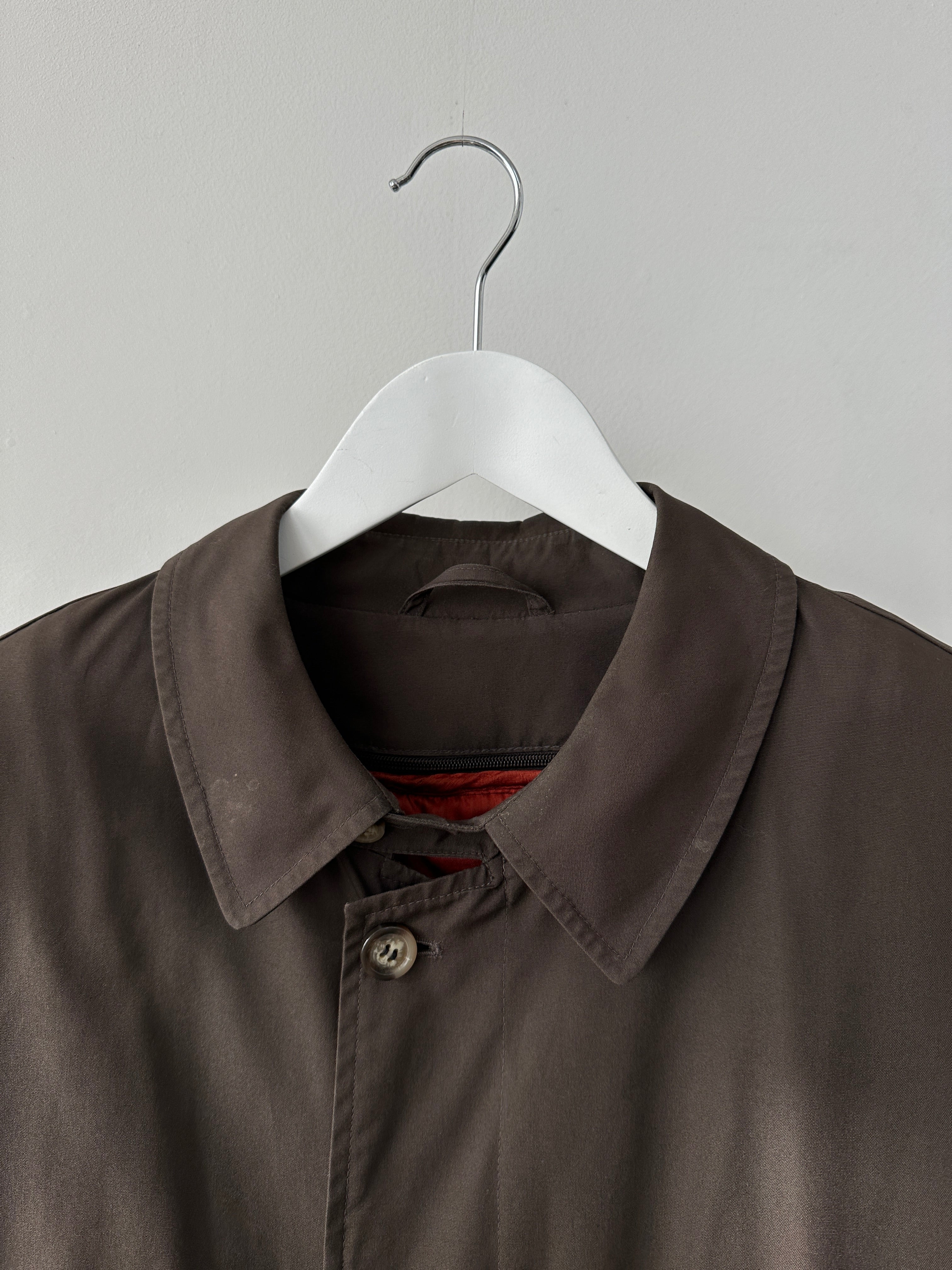 Vintage XXL trench coat with concealed placket, classic design, in neutral fabric, displayed hanging on a wooden hanger.