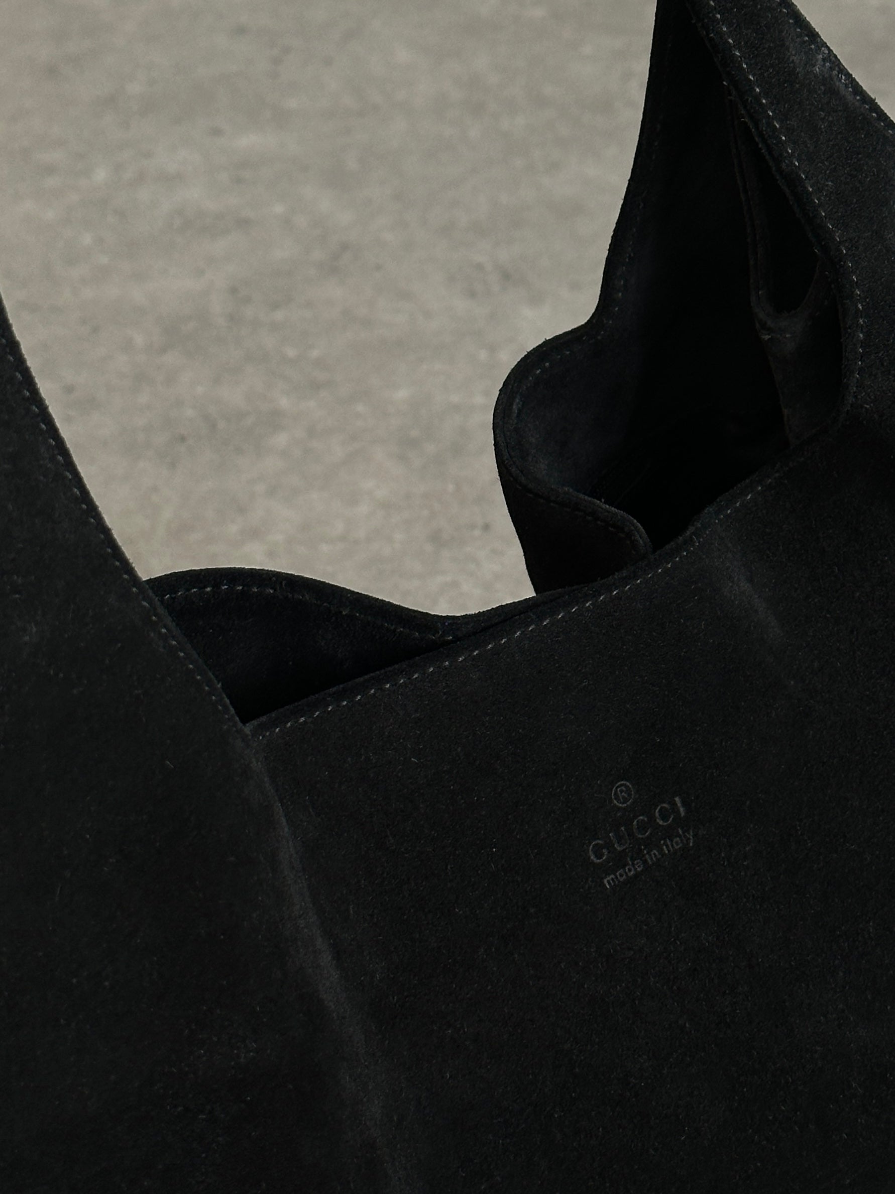 Gucci suede shoulder bag with gold-tone hardware and adjustable strap, featuring the iconic Gucci logo on the front.