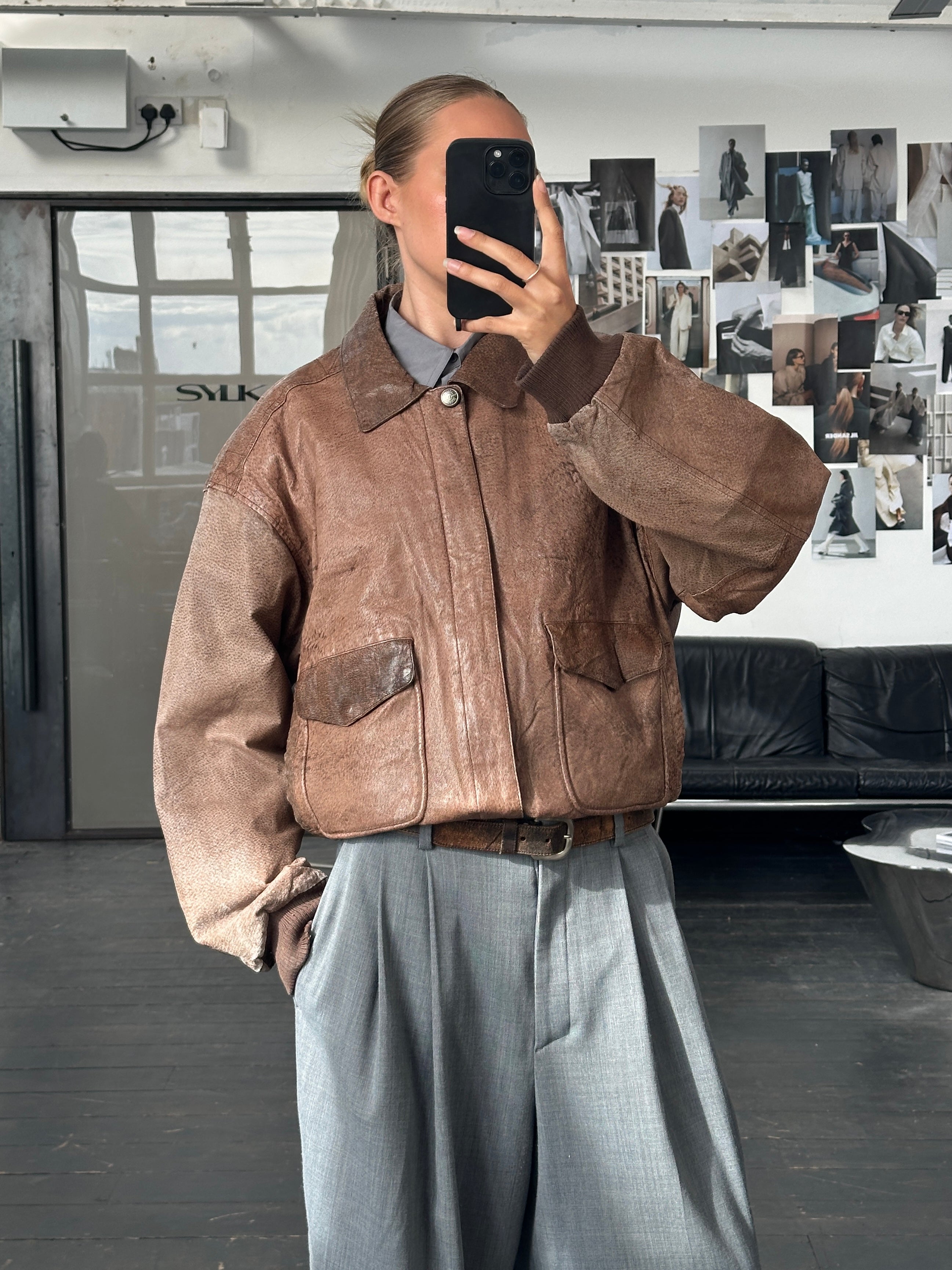 Vintage 1990s leather bomber jacket in size large, featuring classic design with a worn leather finish and ribbed collar.