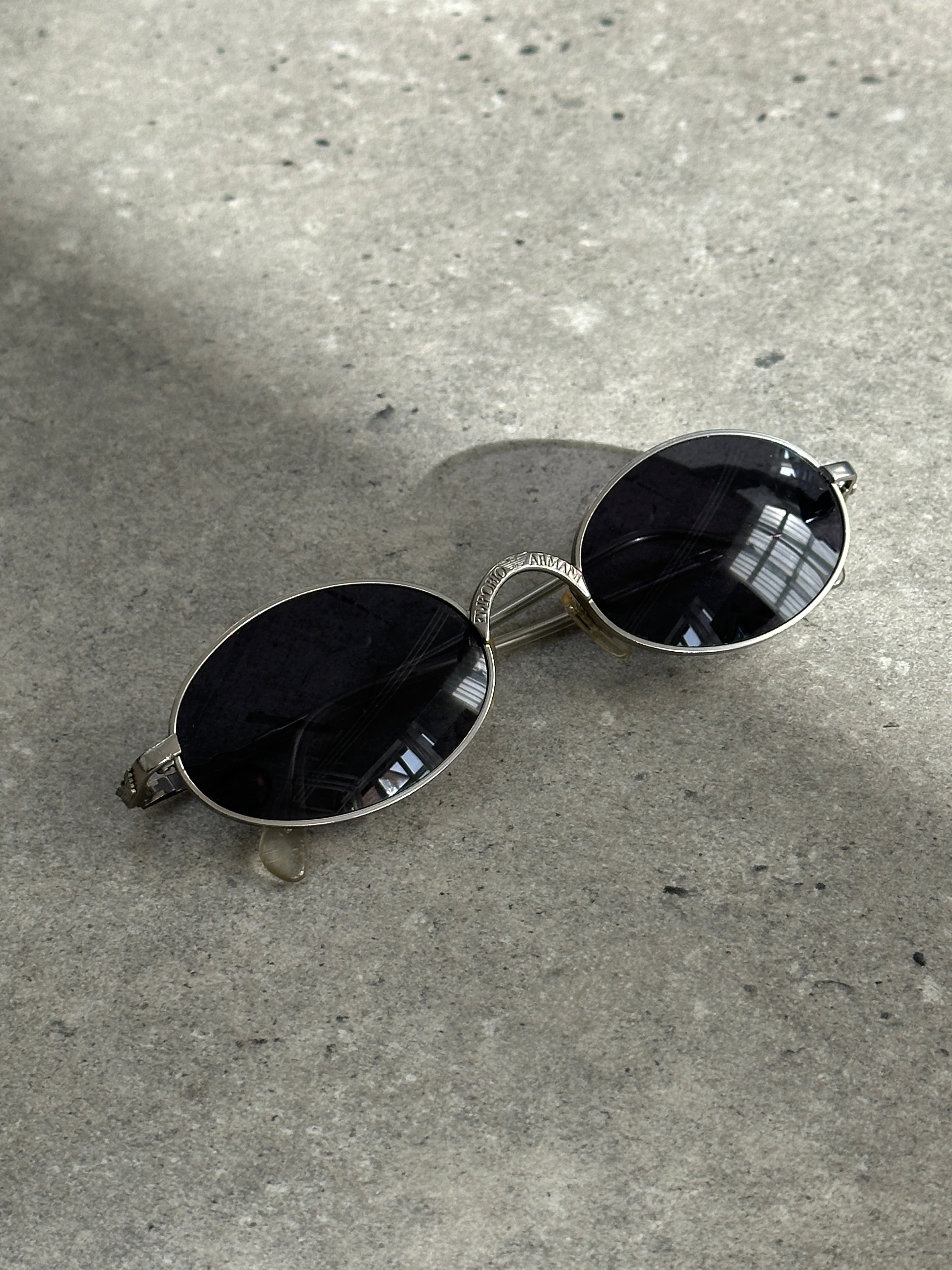 Emporio Armani metal oval sunglasses with dark lenses and sleek silver frames, stylish and sophisticated eyewear.