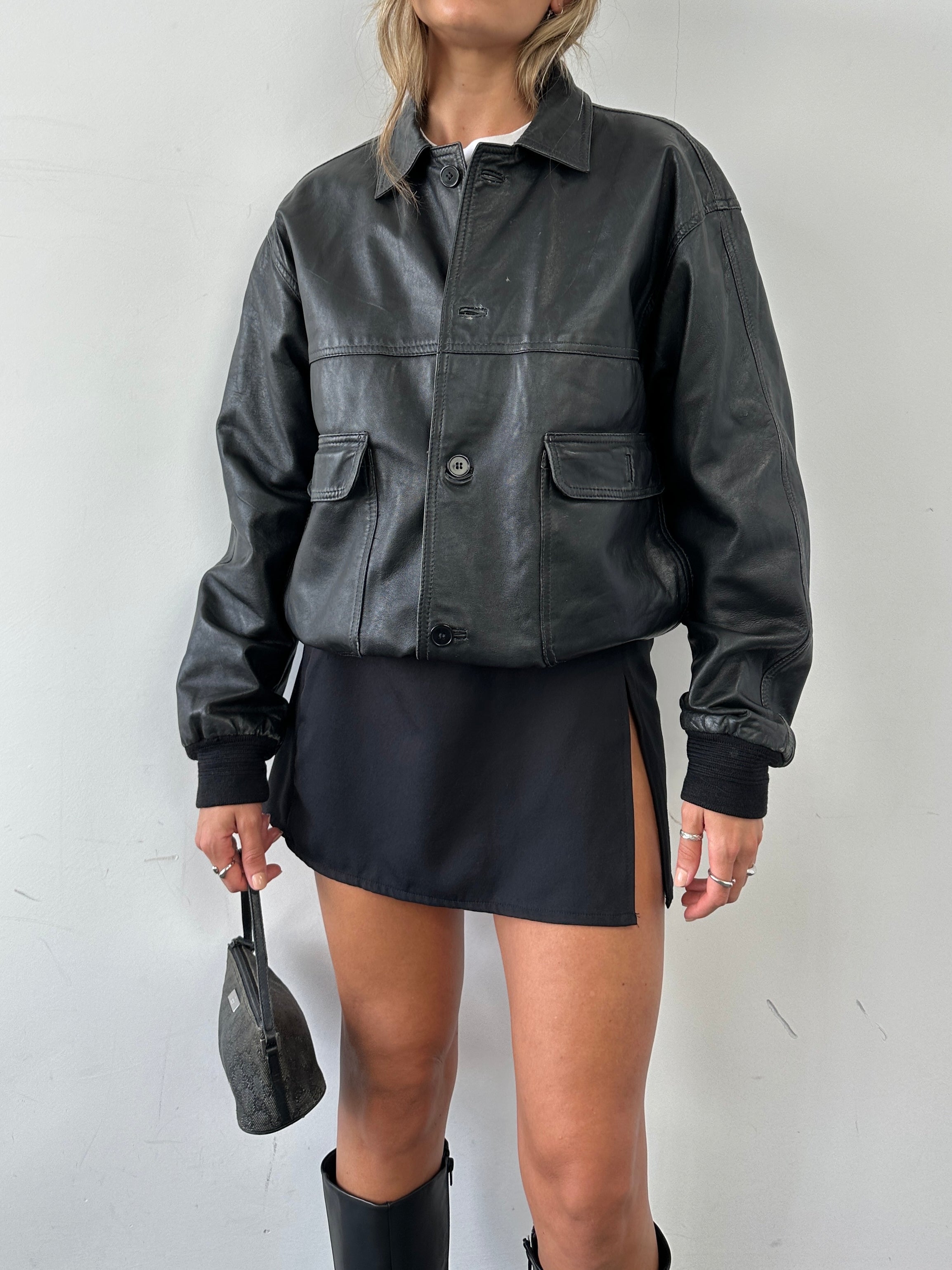 Vintage leather bomber jacket in medium size, featuring classic design with a smooth leather finish and ribbed cuffs.