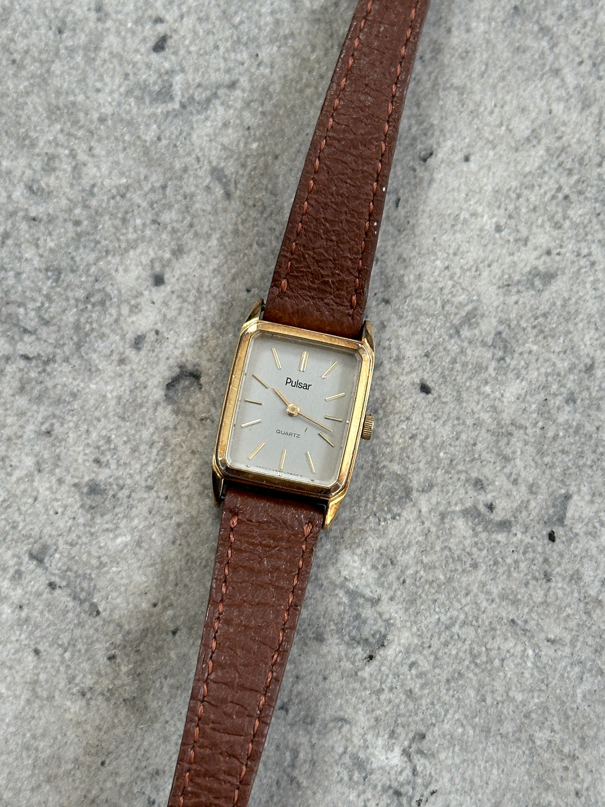 Vintage Pulsar 1980s gold tone leather watch with round dial, classic design, and leather strap.