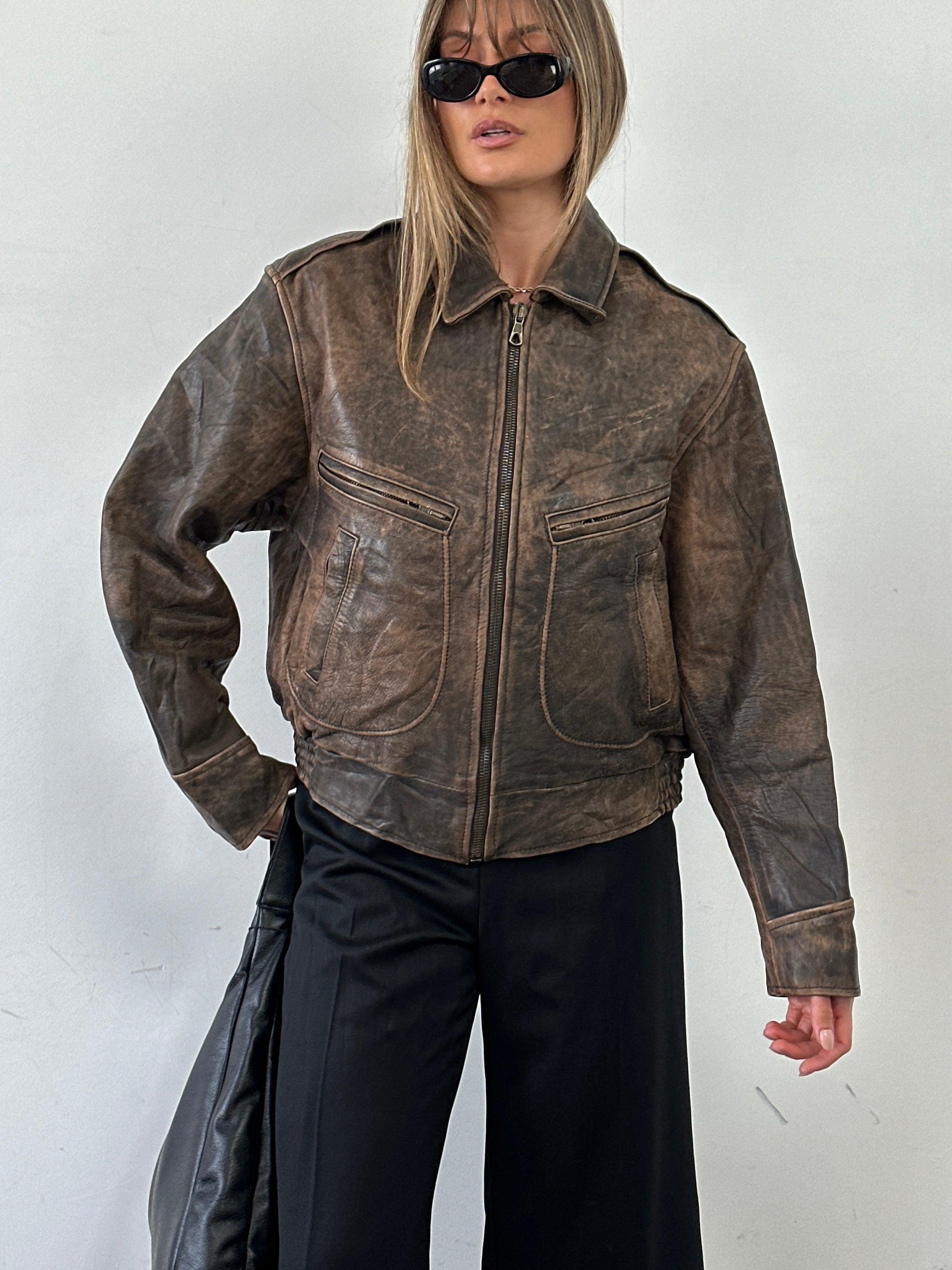Vintage distressed leather bomber jacket in size M/L featuring a rugged, worn-in look and classic style.