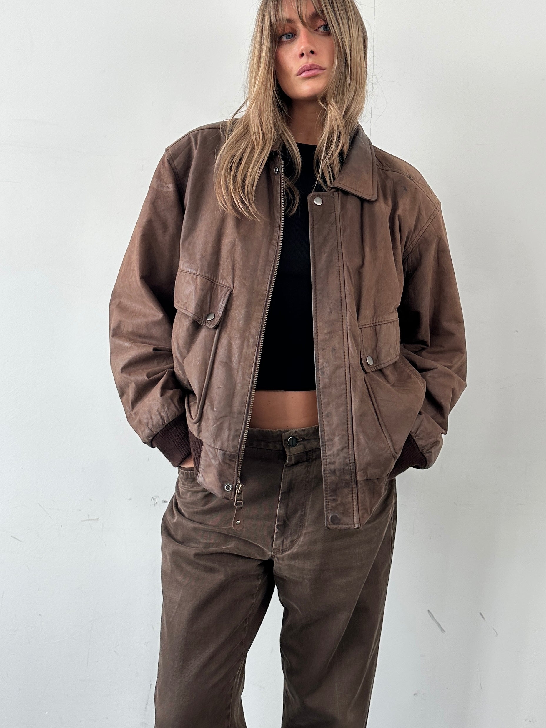 Vintage leather bomber jacket in size large, featuring classic design with ribbed cuffs and collar, shown on a hanger.