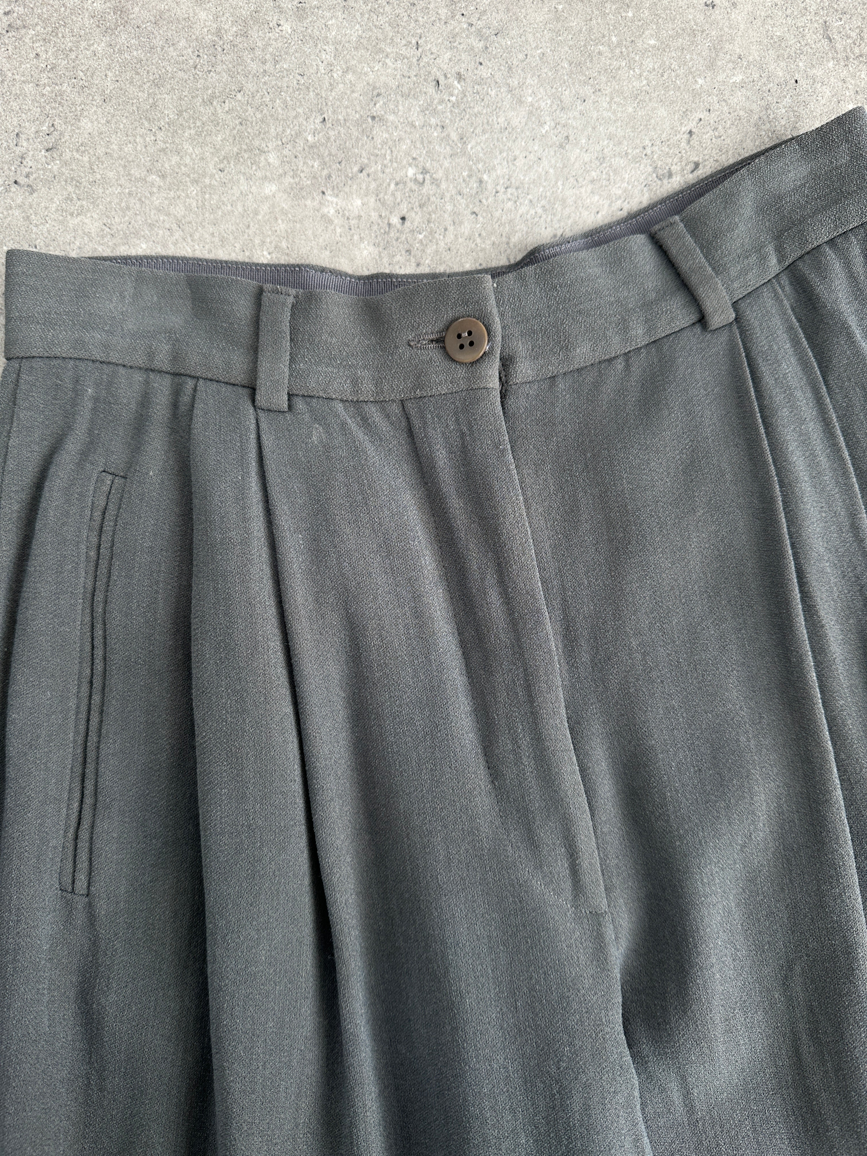 Giorgio Armani high-waisted tapered leg pleated trousers in neutral fabric, displayed hanging on a rack.