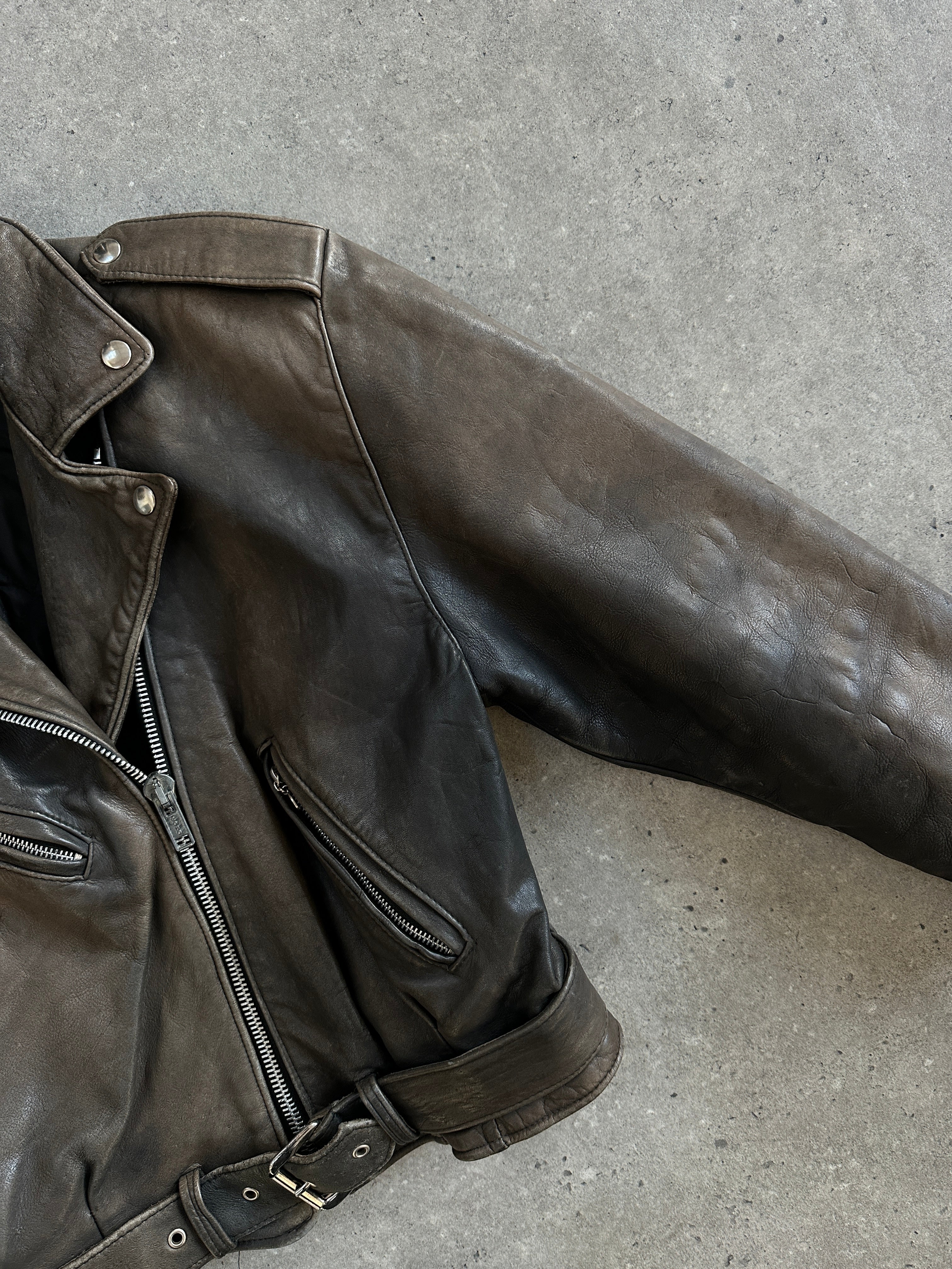 Vintage distressed leather biker jacket from the 1980s, size small, featuring rugged style and classic design details.