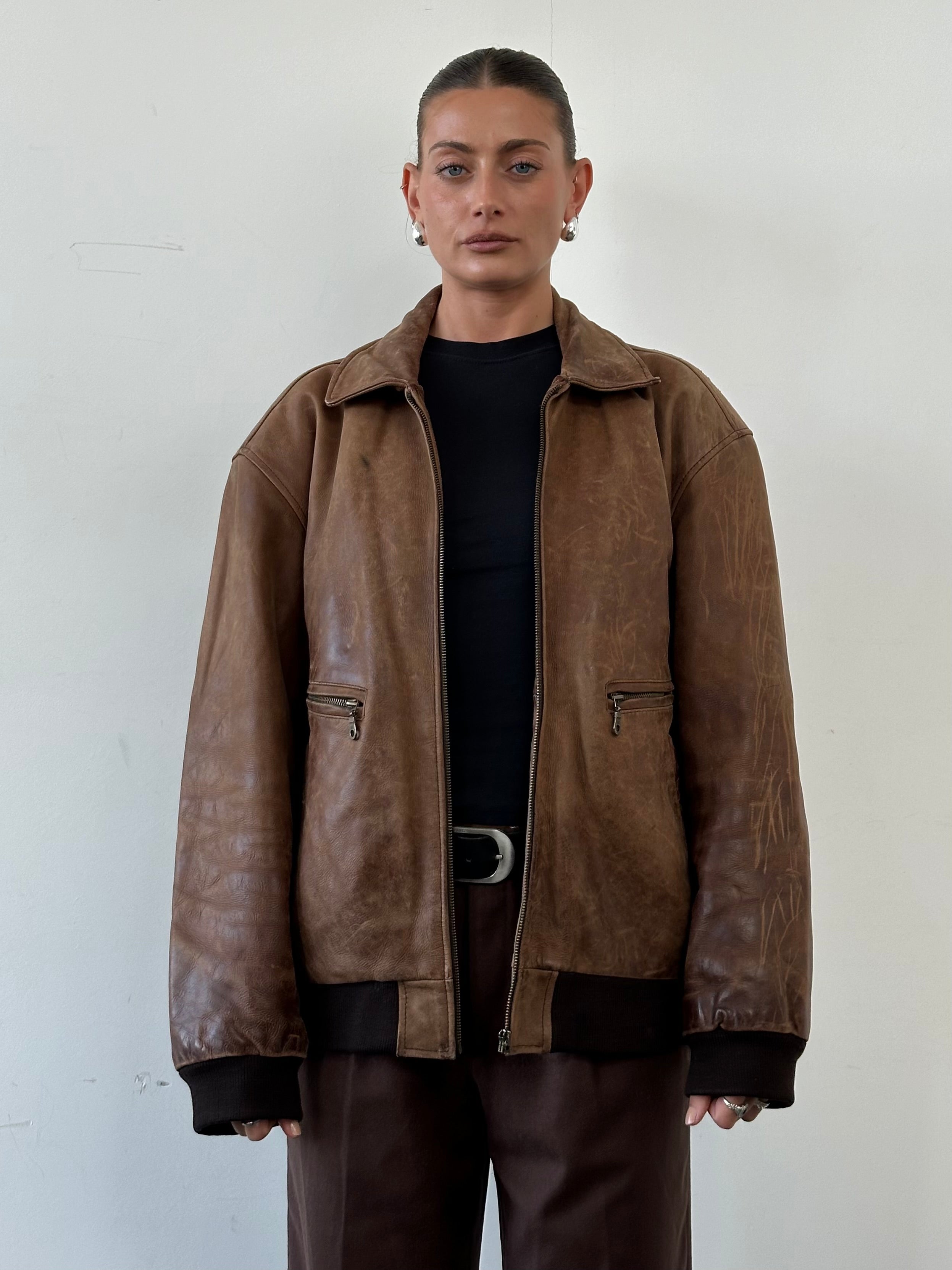 Vintage distressed leather bomber jacket in XL size, featuring rugged texture and classic style.