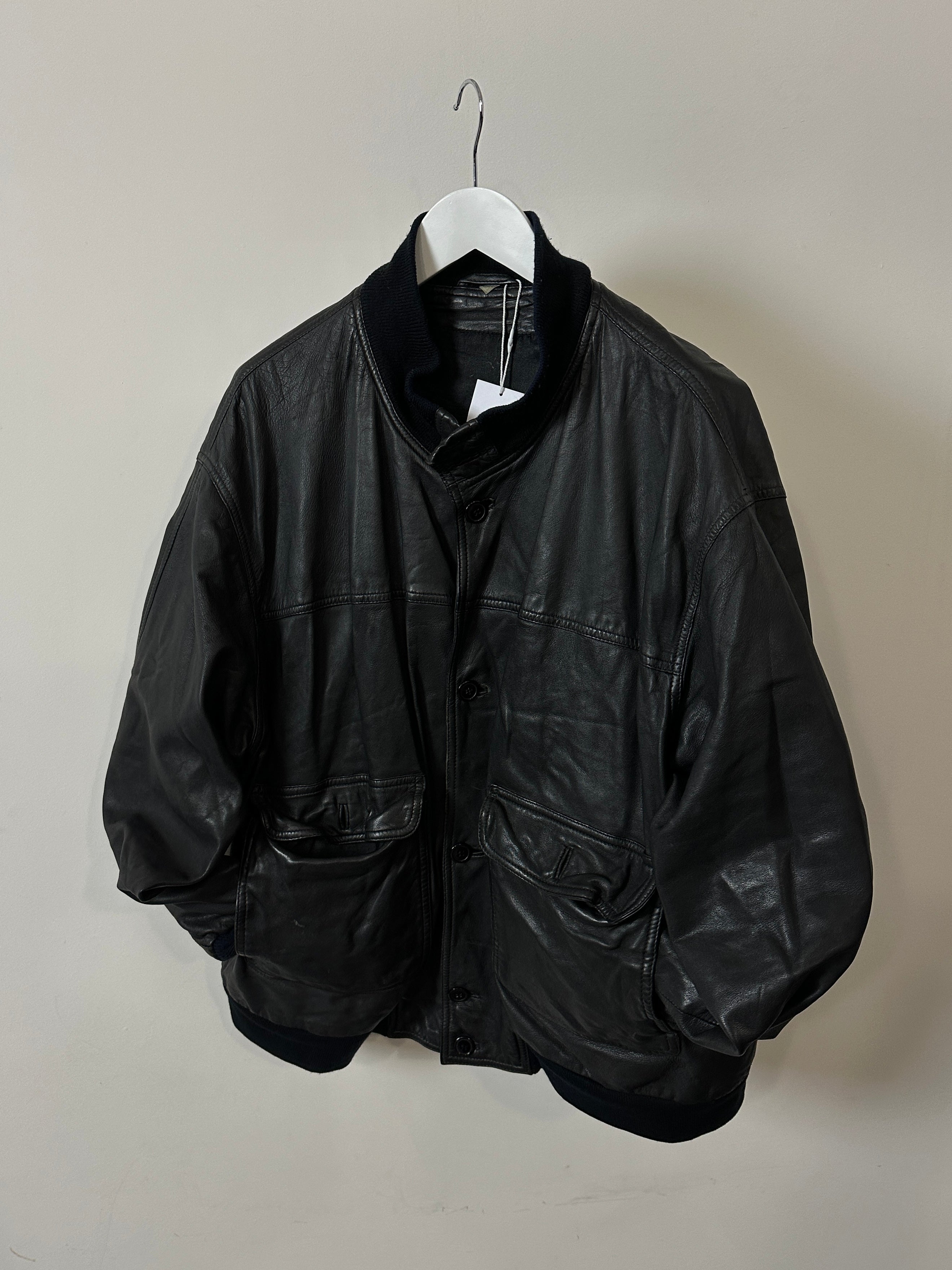 Vintage leather bomber jacket in size L/XL, featuring classic design with ribbed cuffs and collar, displayed on a hanger.