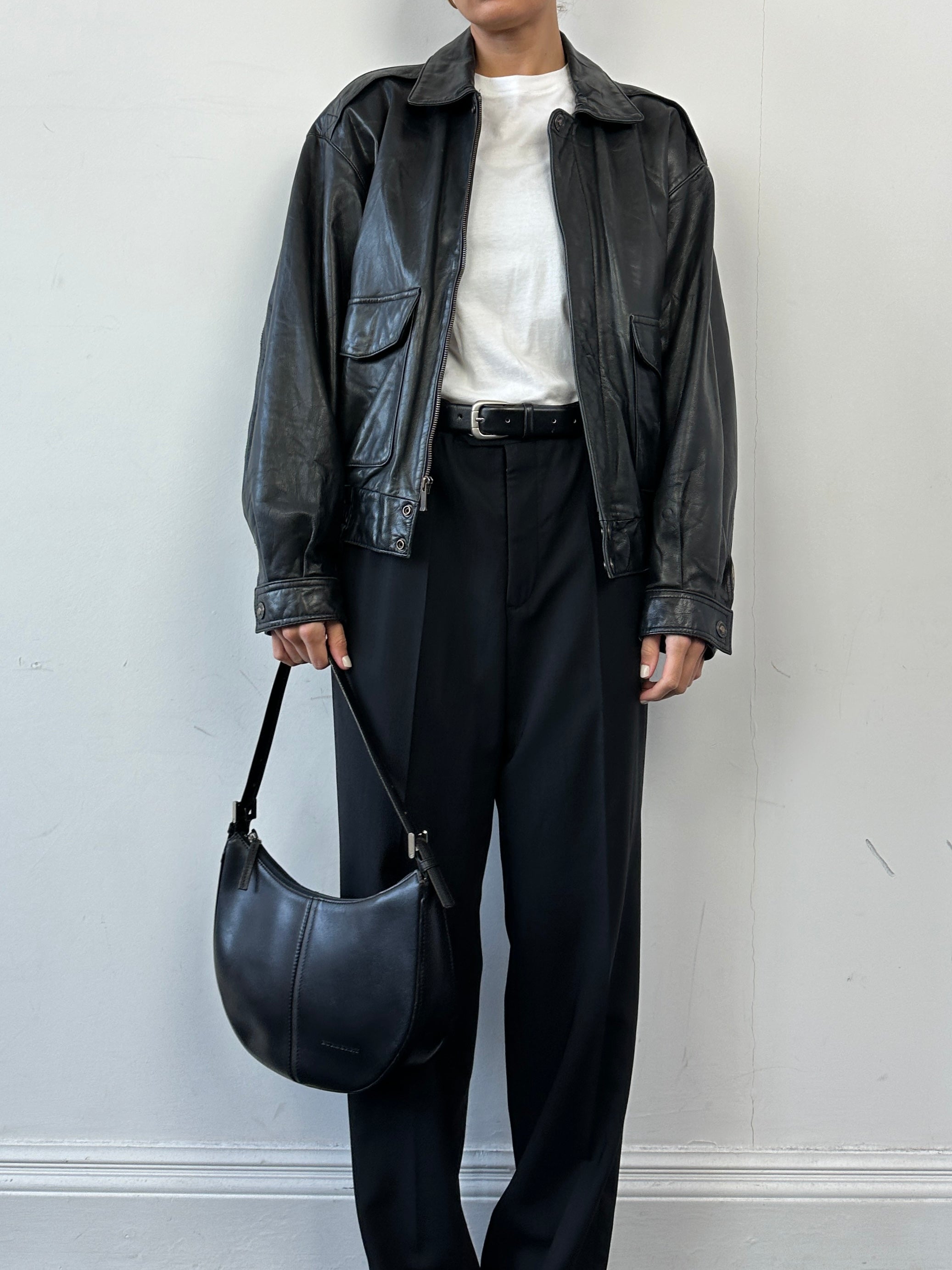 Vintage leather bomber jacket in size S/M, featuring classic design and durable leather material, displayed on a hanger.
