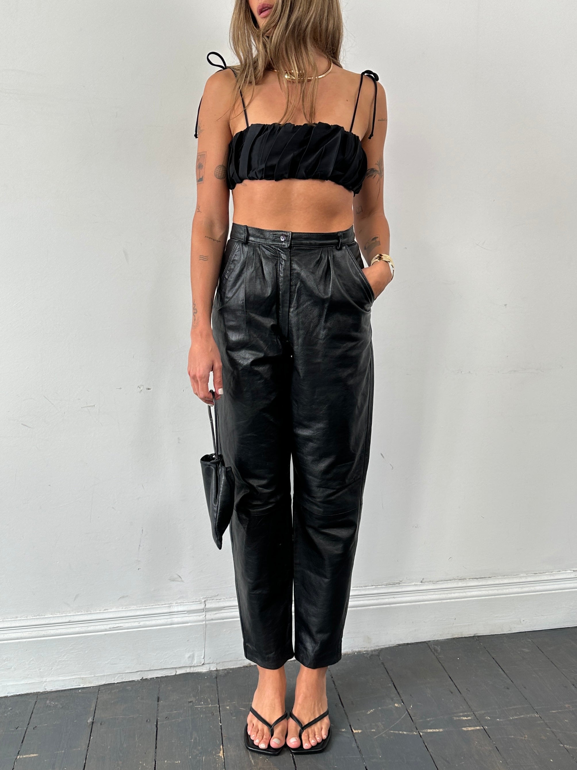 Vintage Italian high waisted tapered leg leather trousers, size W26, with sleek design and classic black leather appearance.