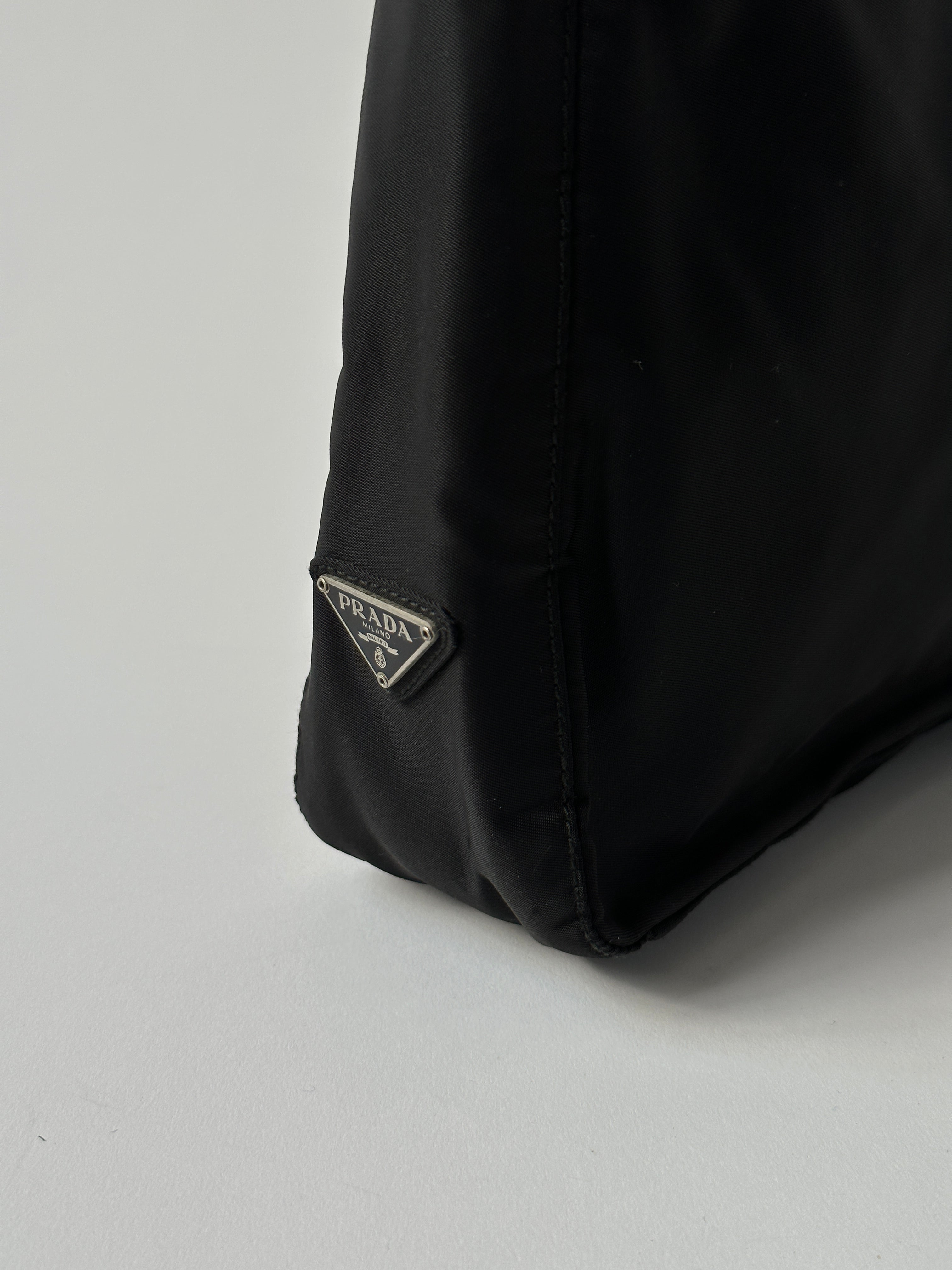 Prada nylon shoulder bag with metal handle, stylish and durable design, featuring sleek black nylon and silver hardware.
