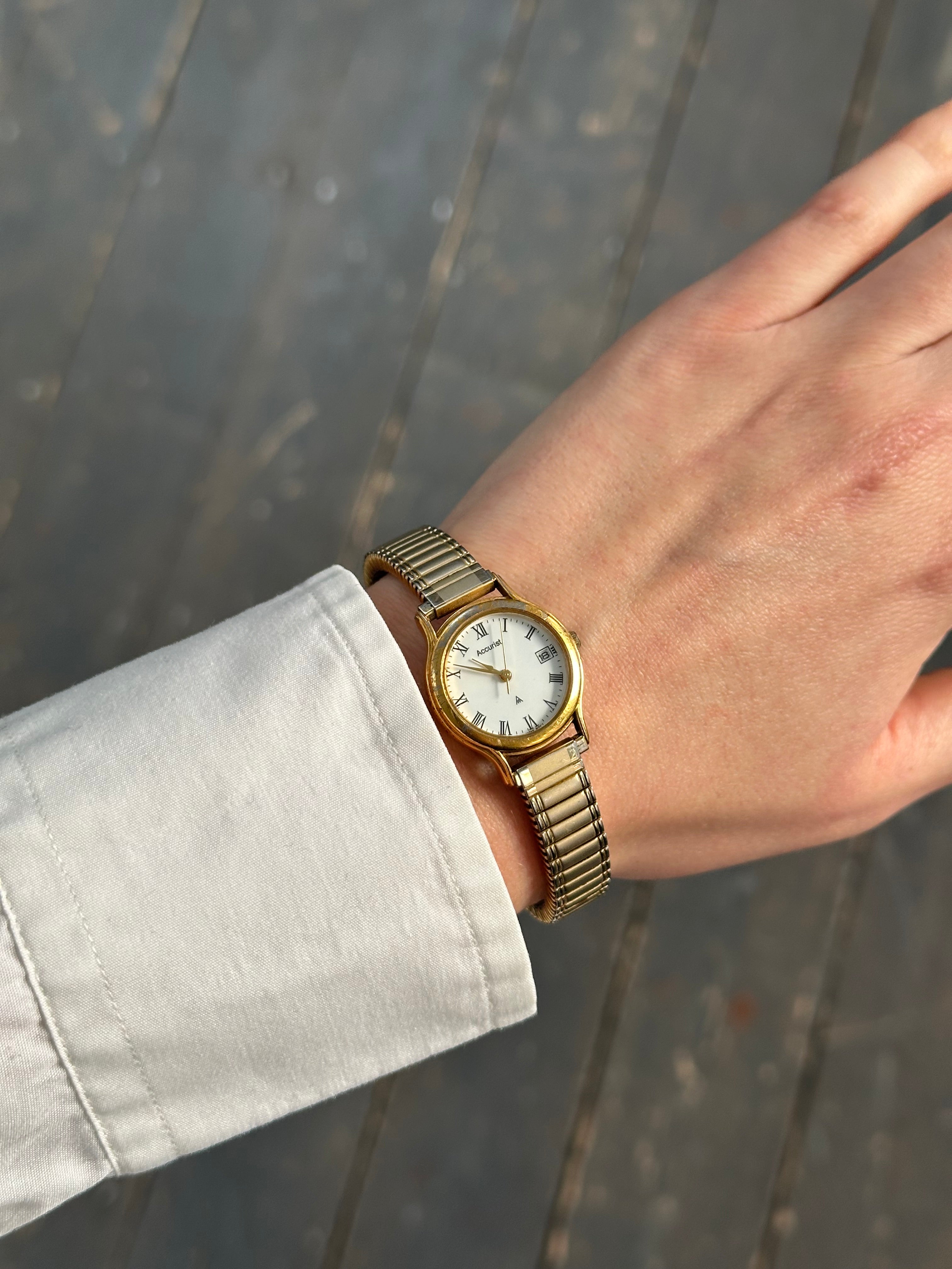 Accurist 1990s gold-tone quartz watch with a classic round dial and metal band, vintage style timepiece.