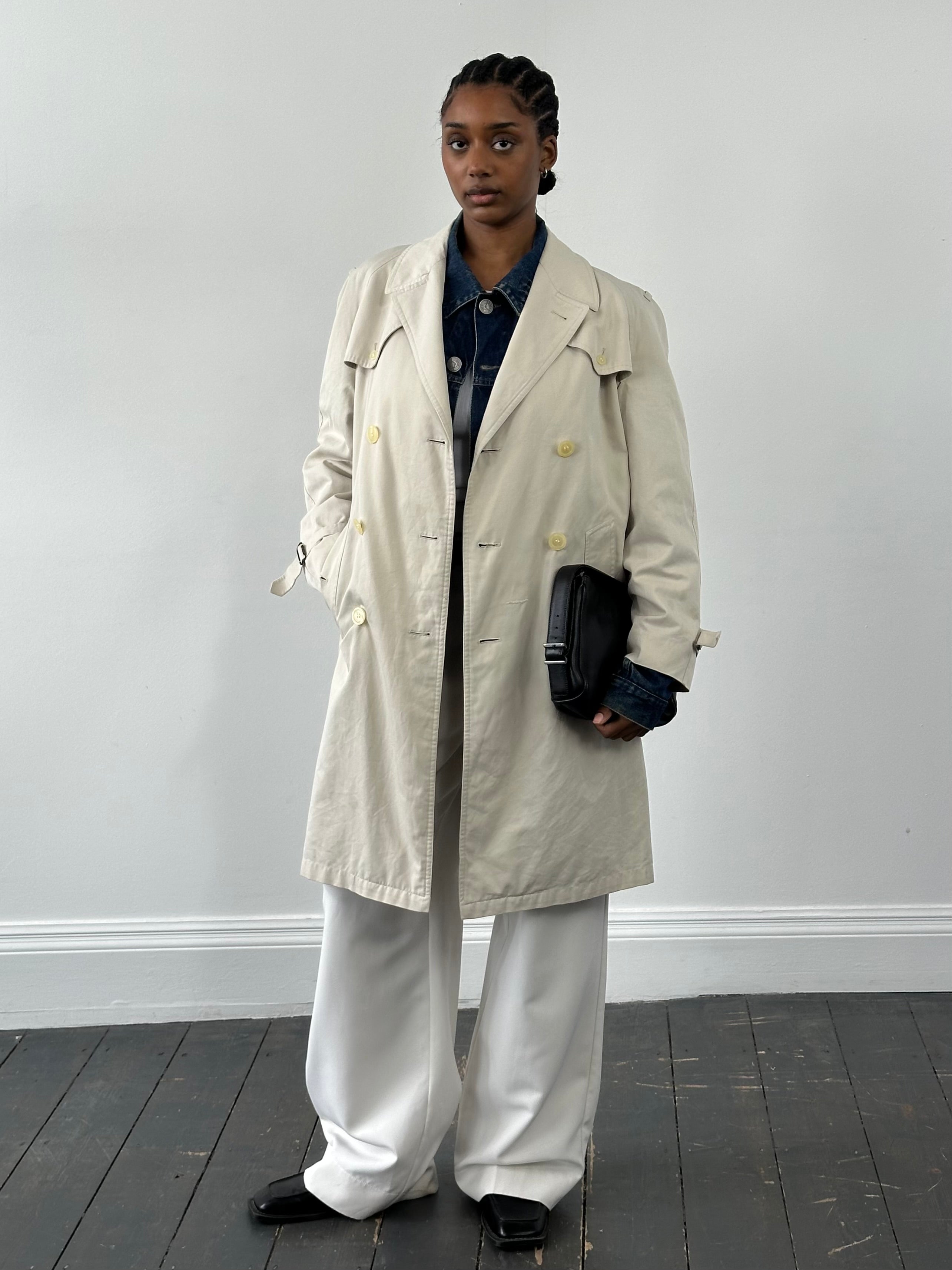 Burberry 1990s cotton double-breasted trench coat displayed on a hanger, featuring classic beige color and signature style details.