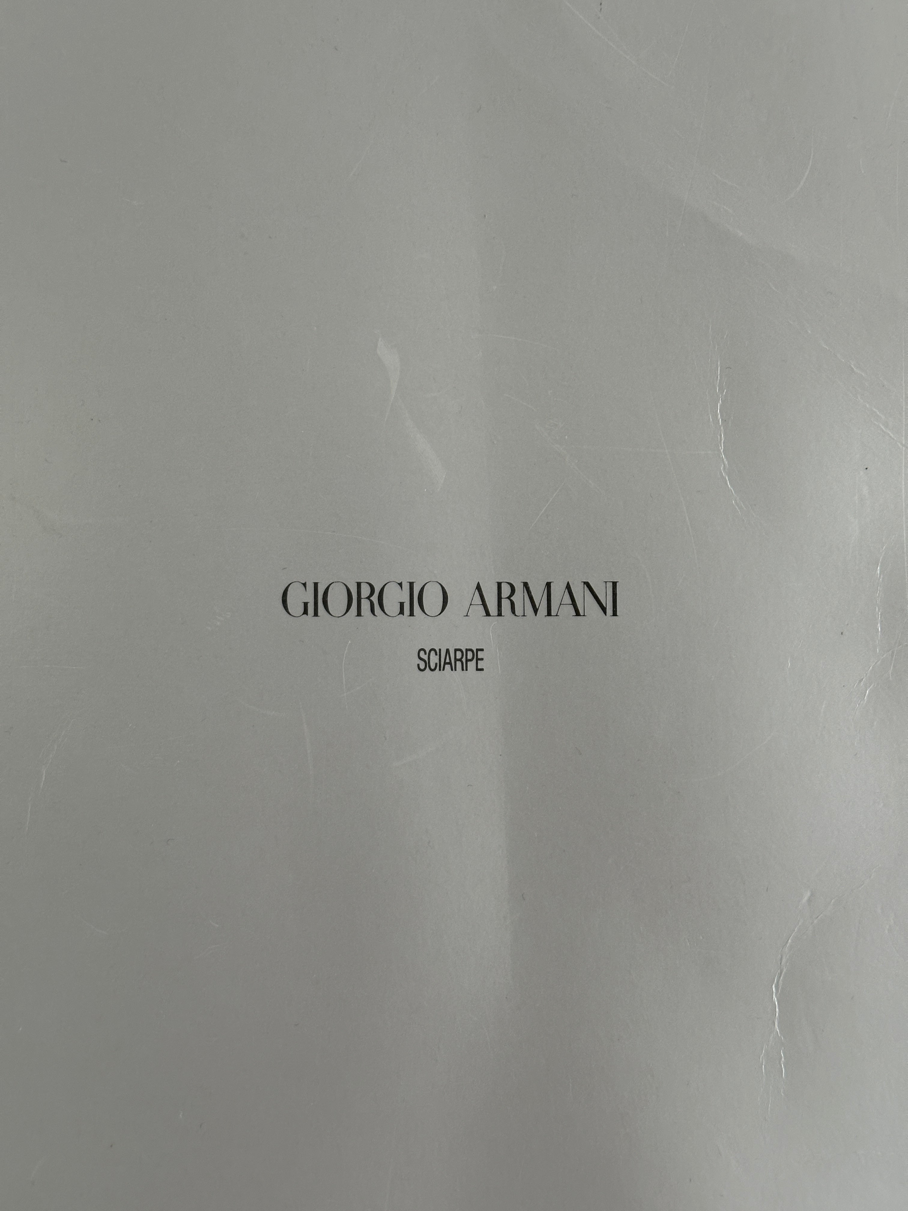 Giorgio Armani Le Collezioni pure wool logo scarf in neutral tones, displaying the elegant Armani branding and soft wool fabric.