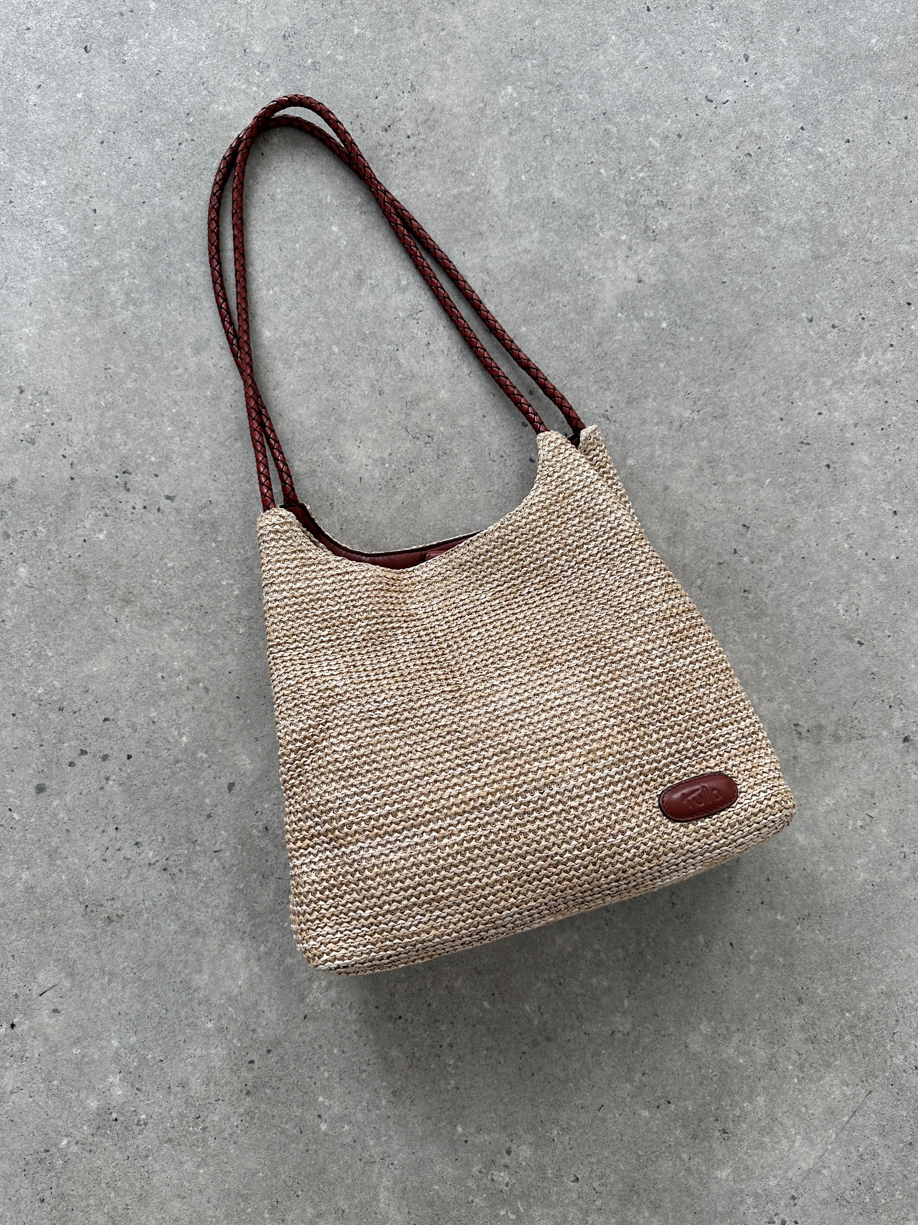 Vintage leather and straw shoulder bag with adjustable strap, featuring a rustic, stylish design perfect for casual outings.