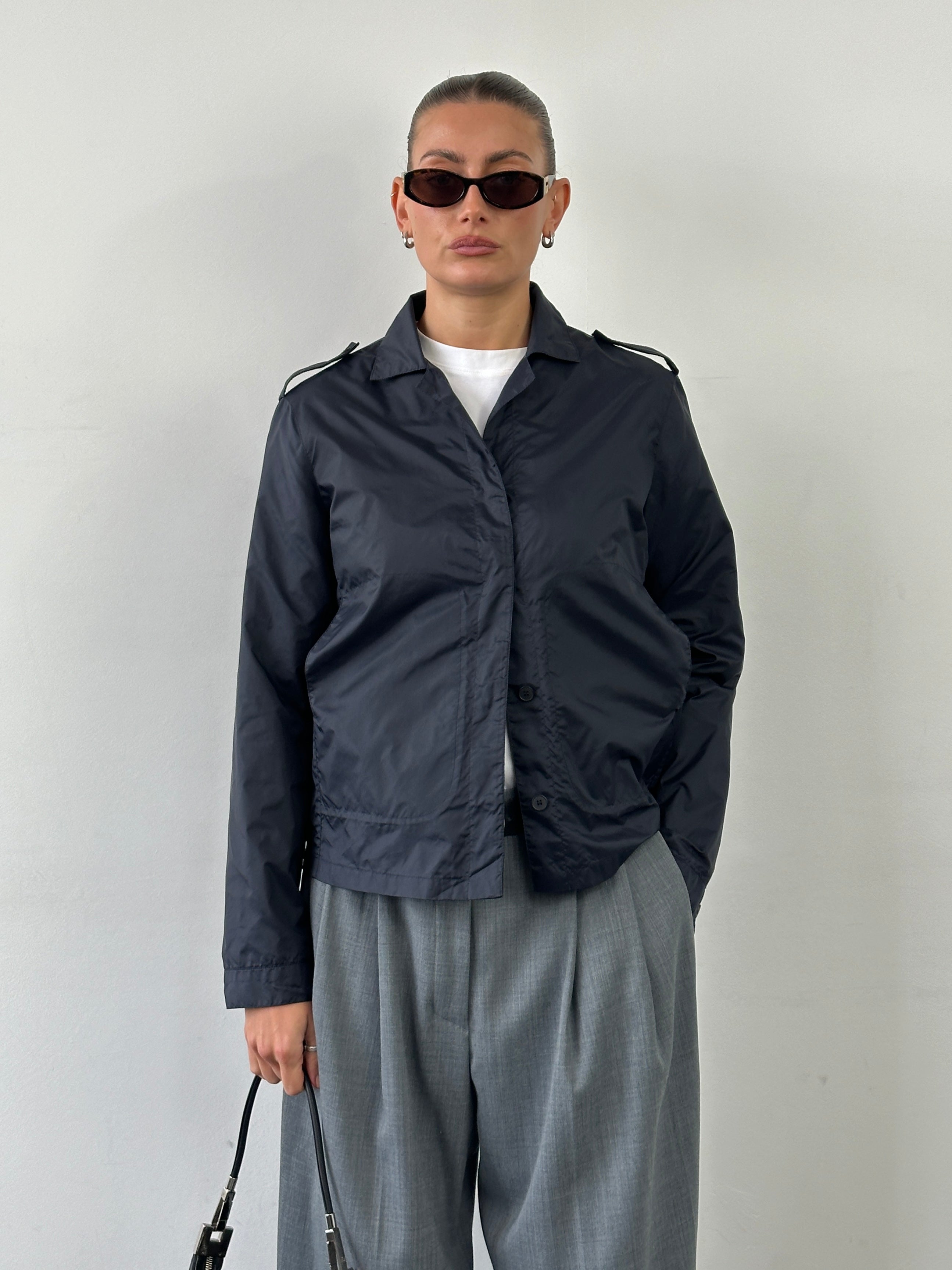 Armani Jeans 1990s showerproof nylon lightweight logo jacket in black, showing front view with Armani logo details.