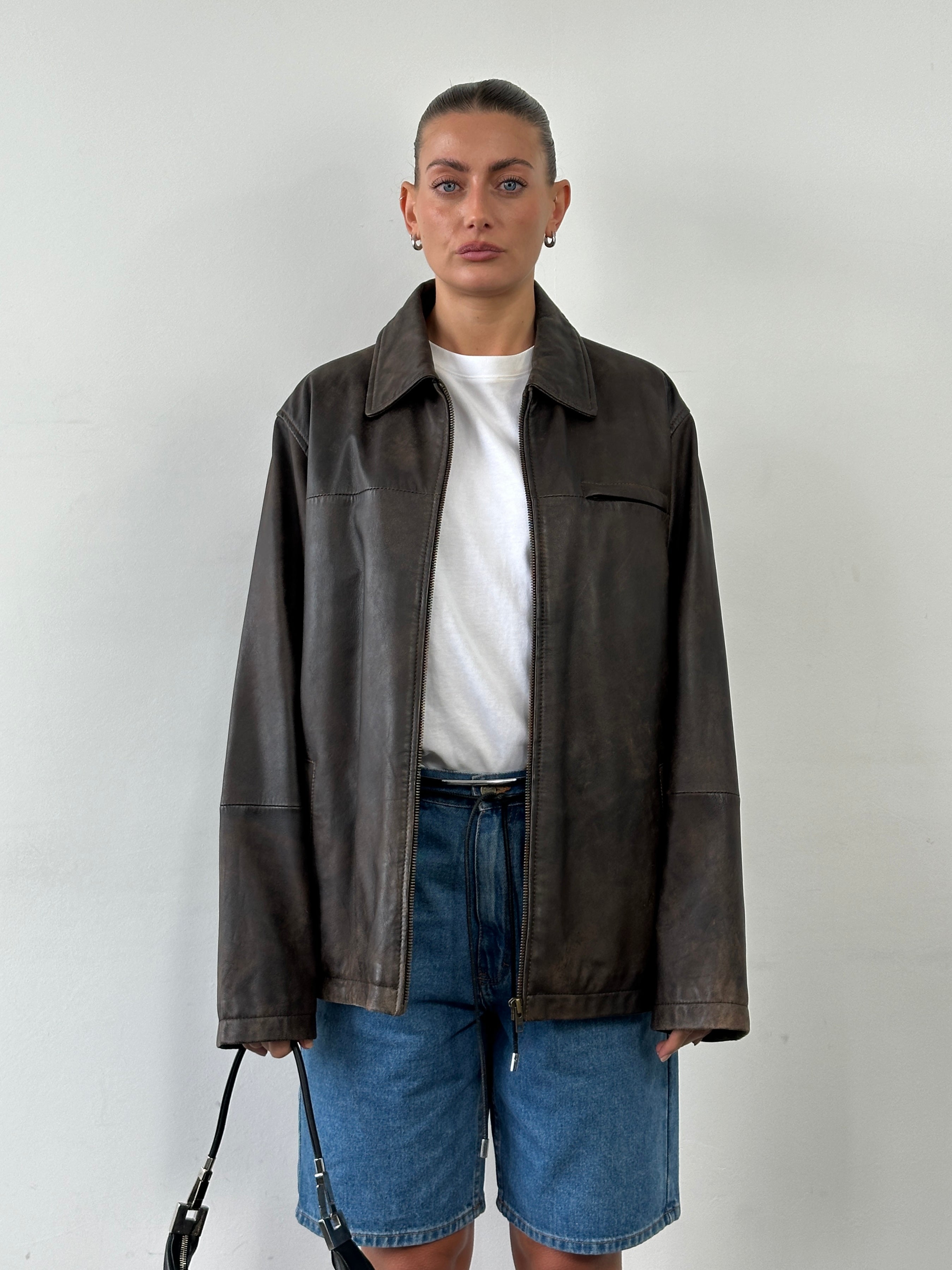 Vintage minimal aged leather jacket in XL size, showing distressed brown leather with classic collar and button details.