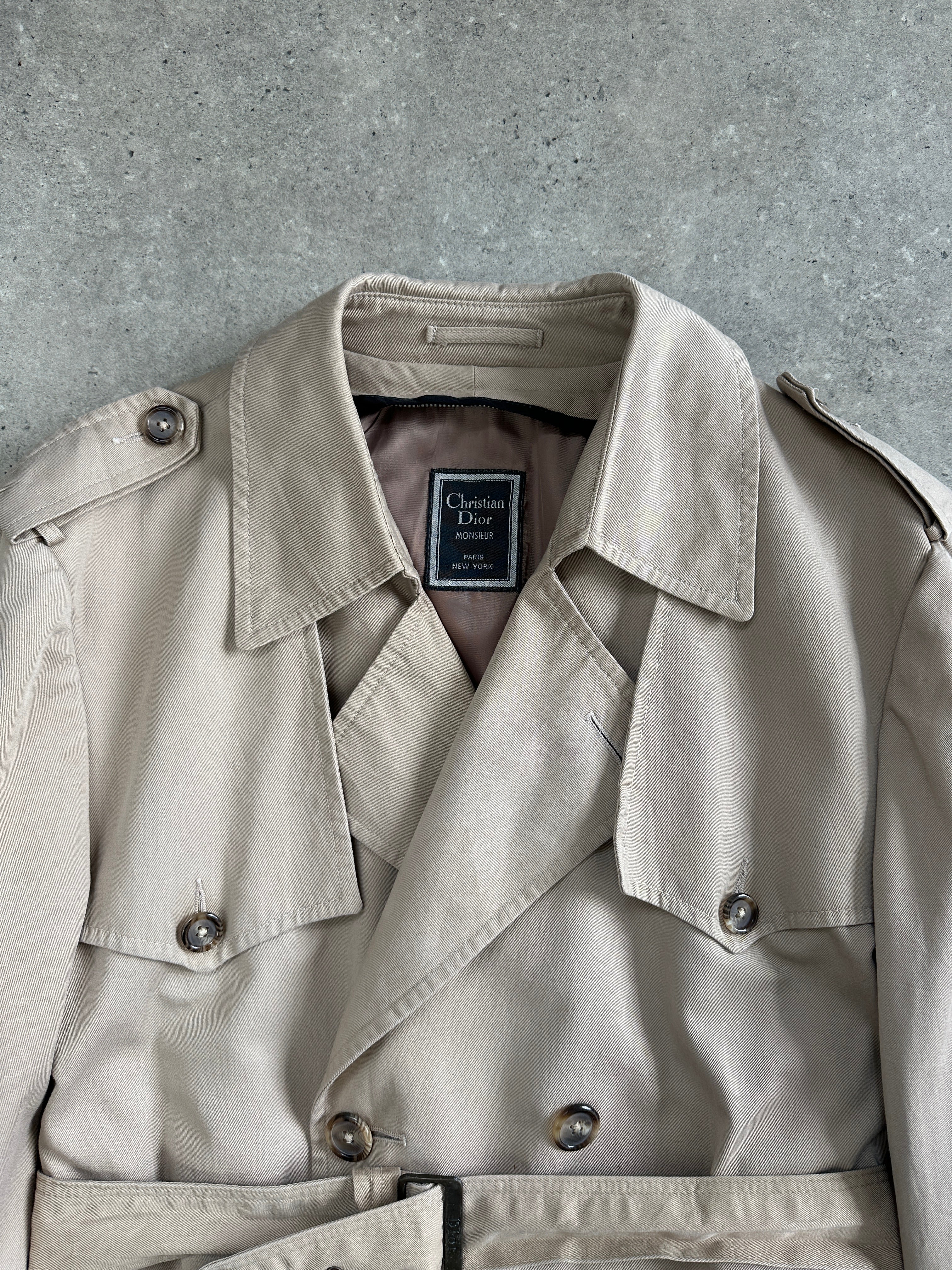 Christian Dior Monsieur cotton double-breasted belted trench coat in size L/XL, shown hanging with classic design and neutral color.