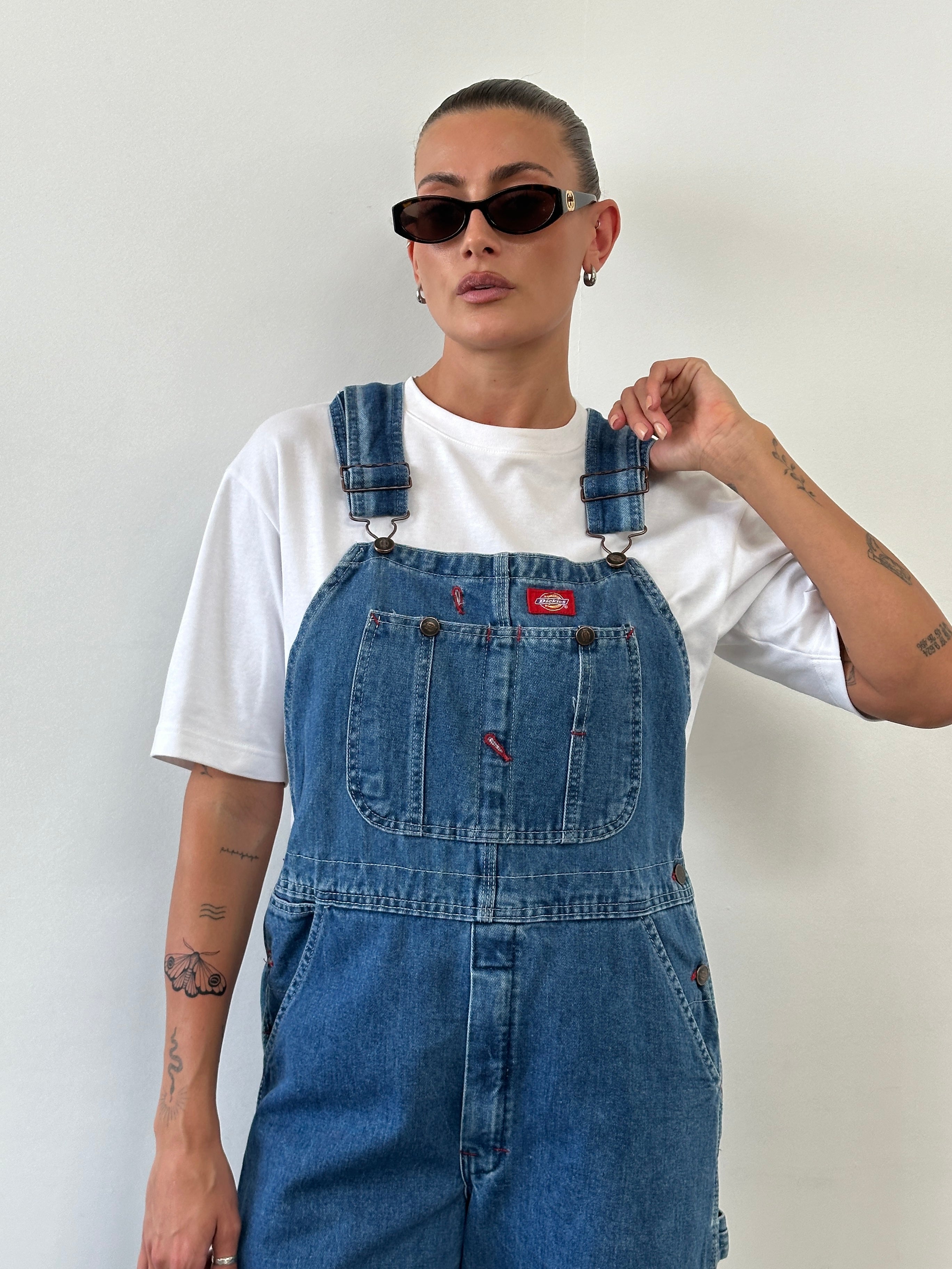Dickies pure cotton denim dungarees displayed on a model, featuring classic front pockets and adjustable shoulder straps.