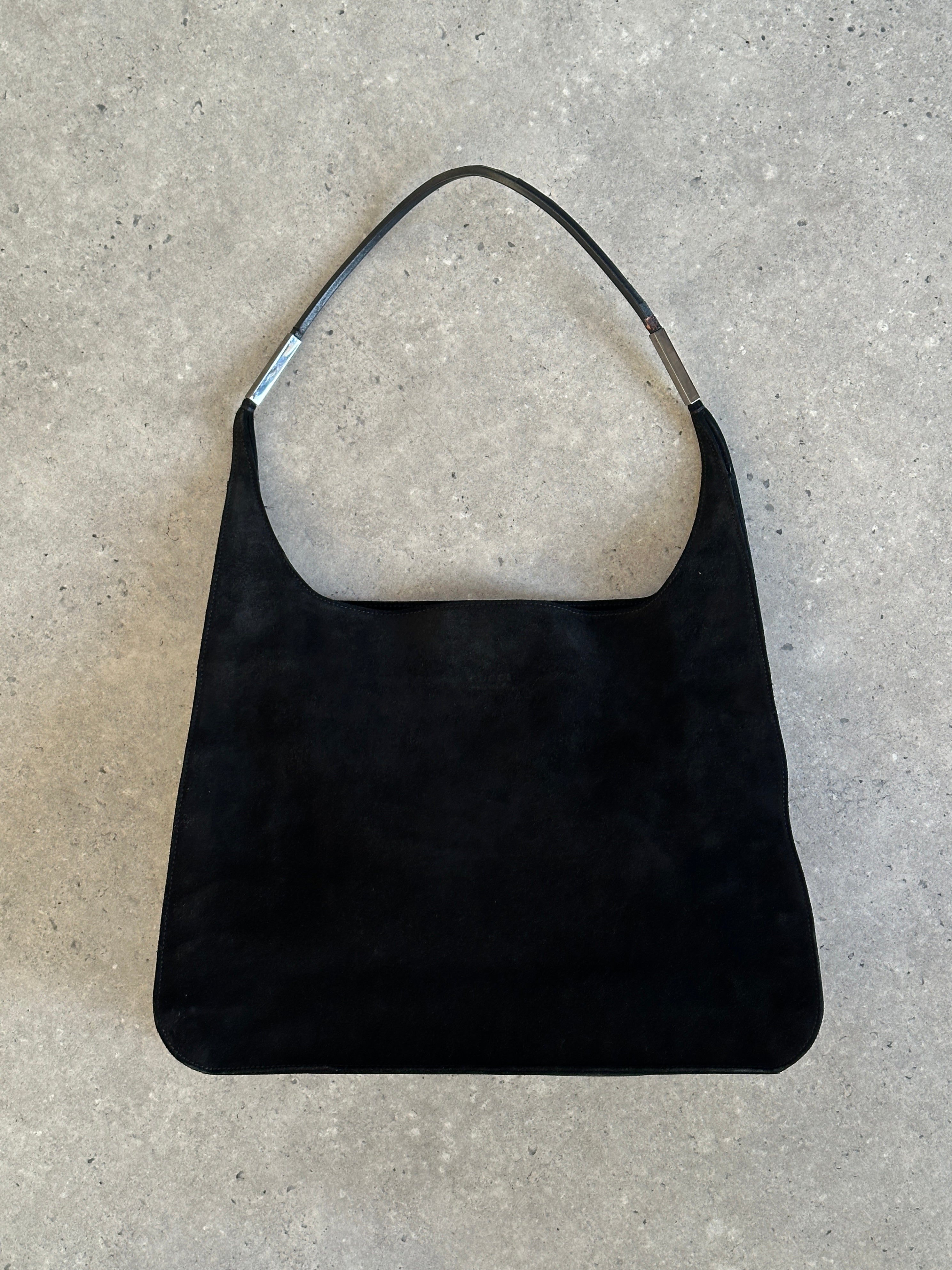 Gucci suede shoulder bag with adjustable strap, featuring a sleek design and subtle logo detail.