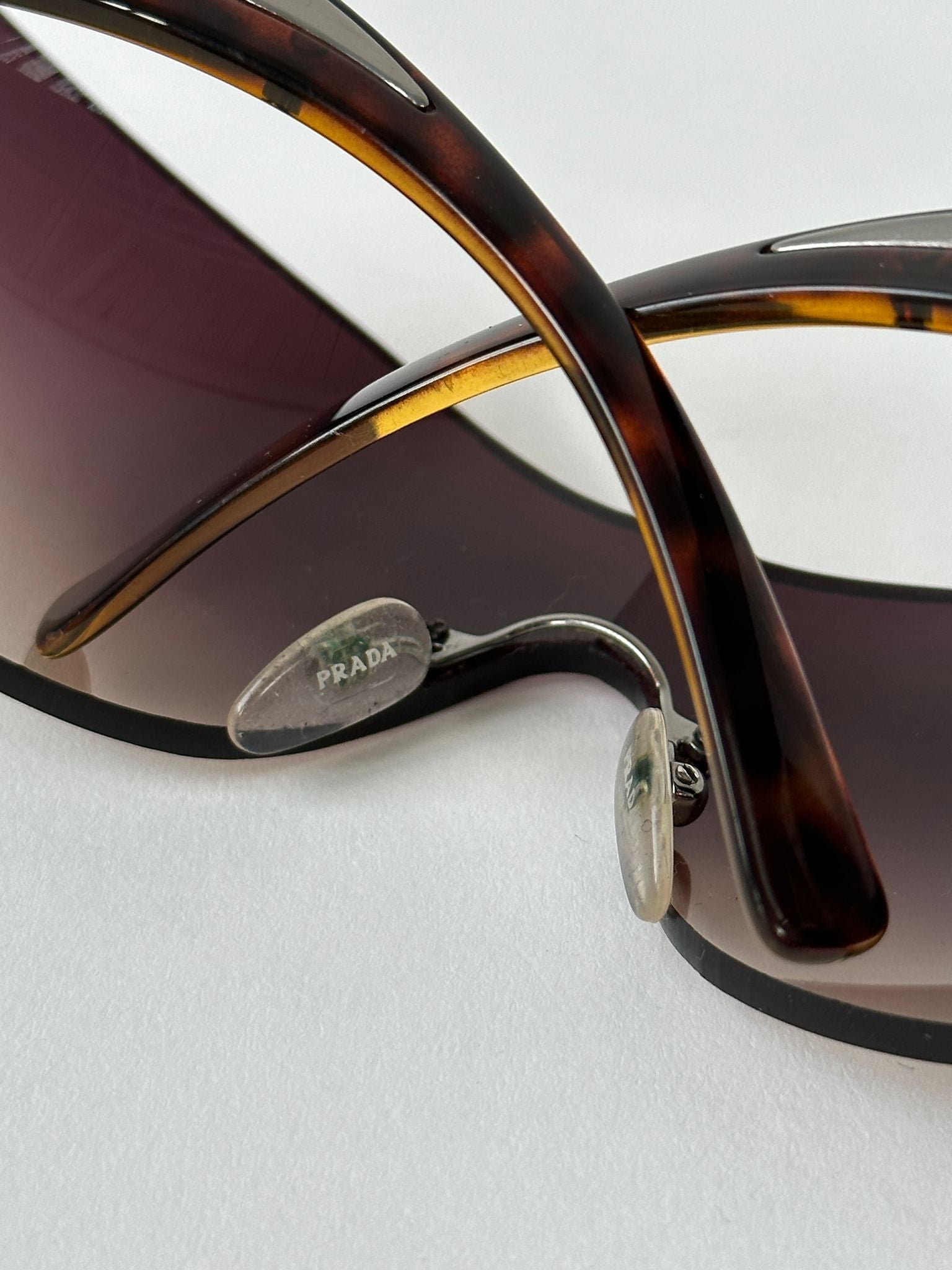 Prada Flame Rimless Wrap Sunglasses with sleek black frames and tinted lenses, stylish eyewear for sun protection.