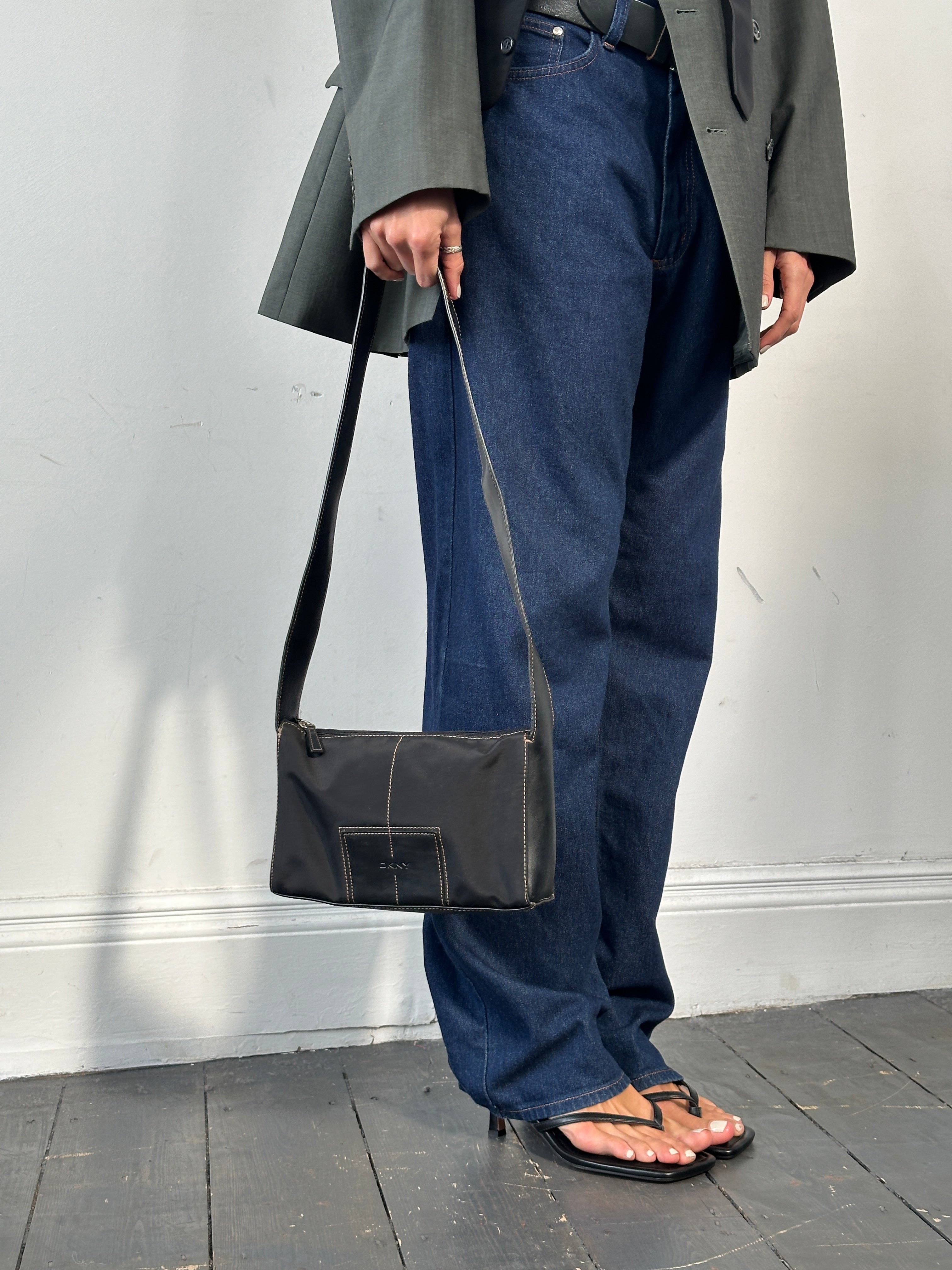 DKNY contrast stitch crossbody bag with adjustable strap and sleek design, featuring stylish contrast stitching details.