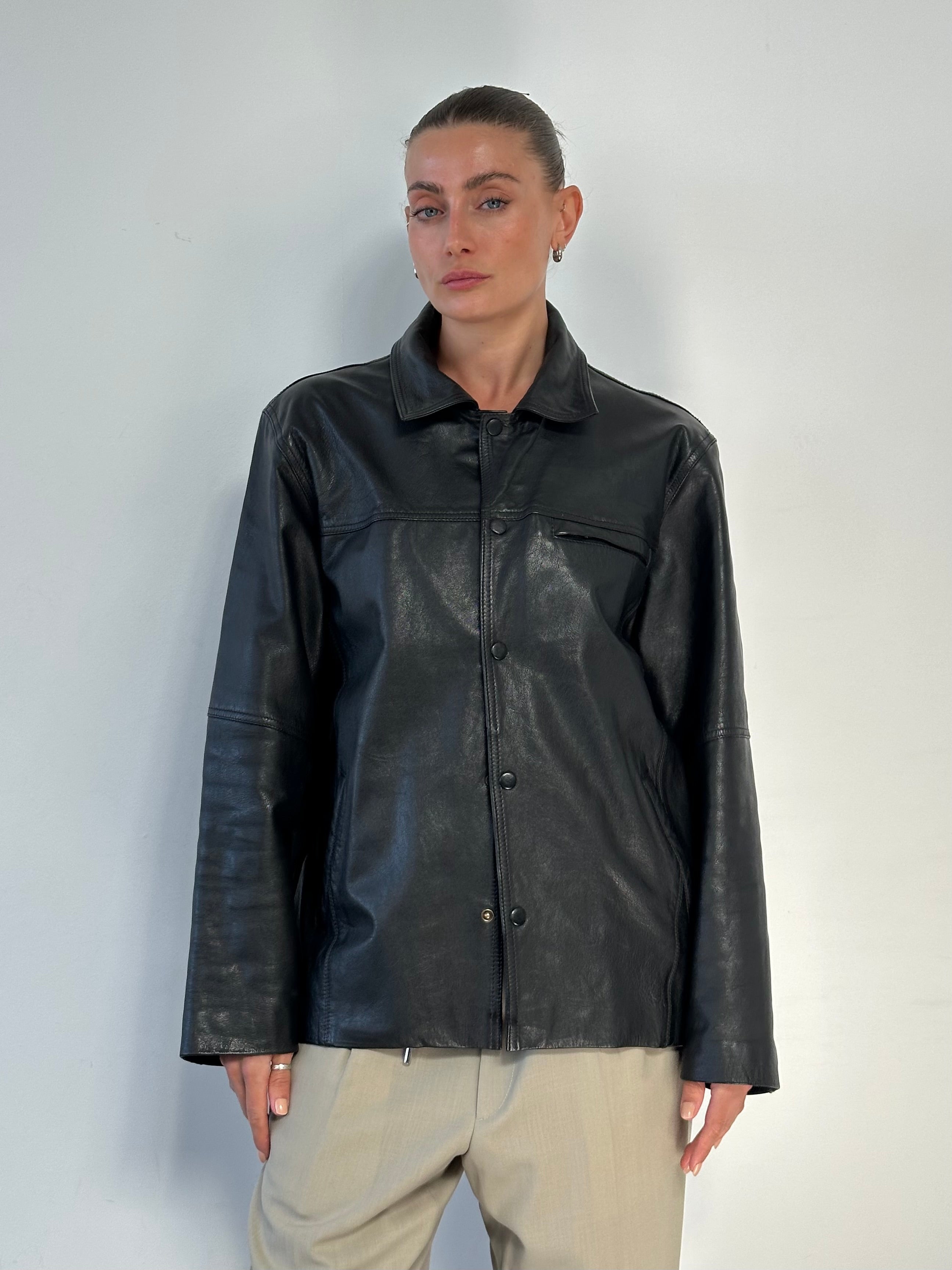 Vintage minimal leather jacket in size M/L, featuring a sleek design and classic style, displayed on a hanger.