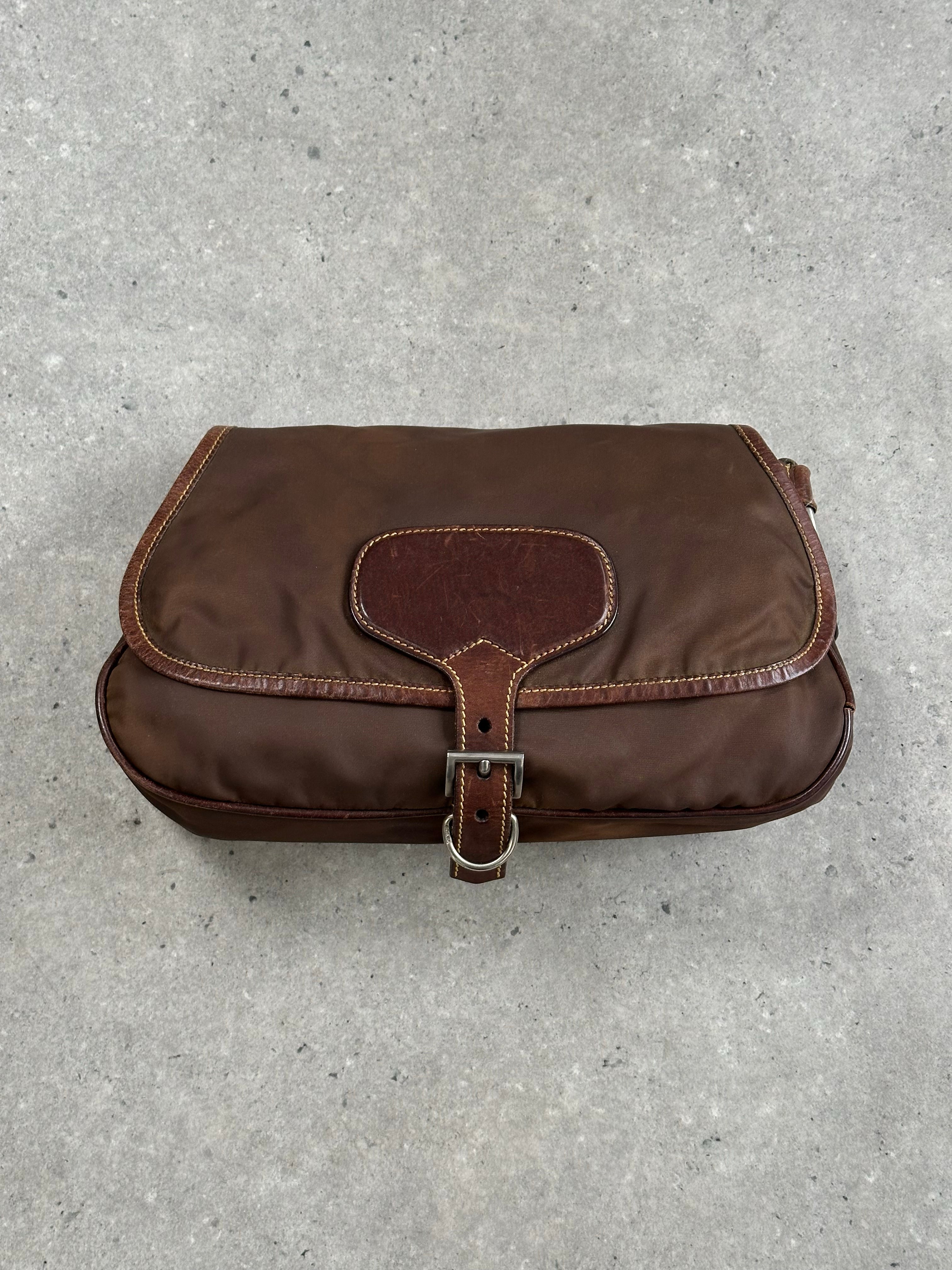 Prada 1990s nylon crossbody bag with adjustable strap and logo detail, featuring a sleek black design and compact shape.