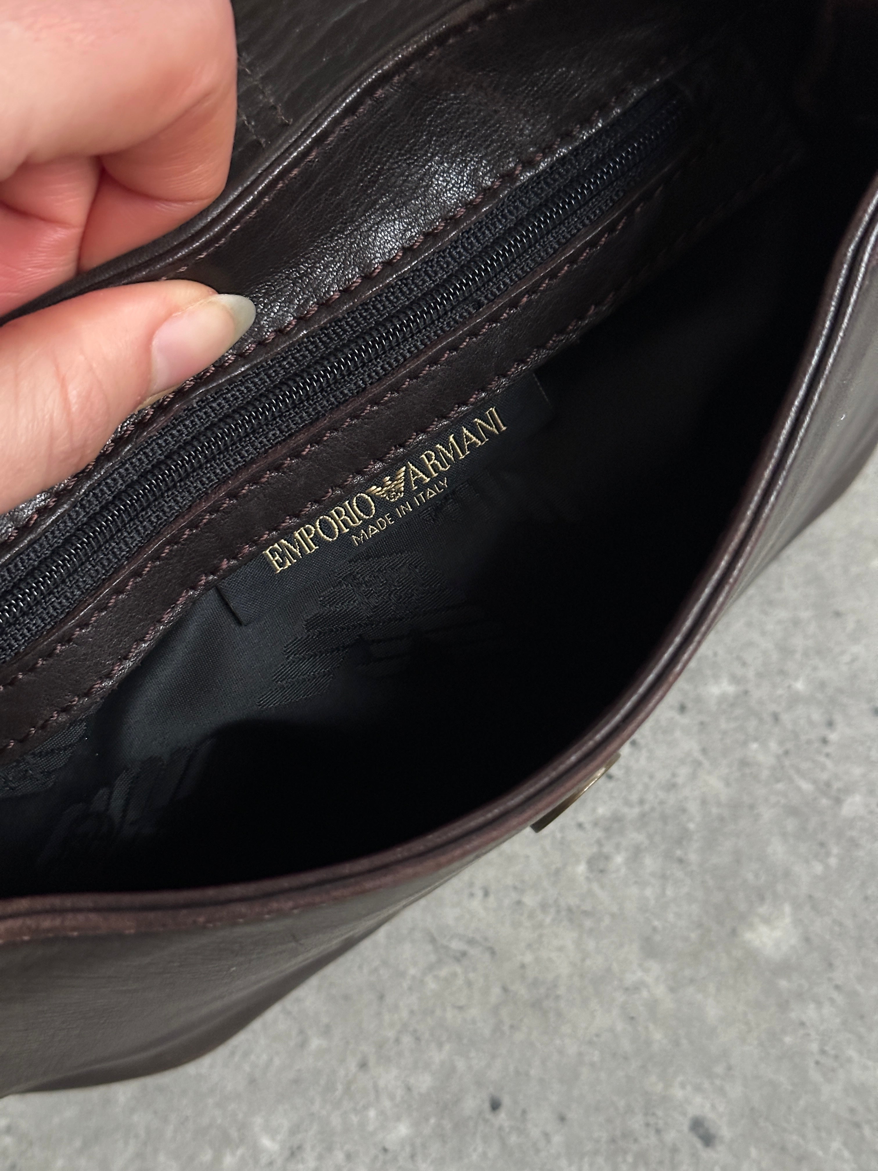Emporio Armani leather shoulder bag with hardware monogram design, featuring a sleek strap and structured silhouette.