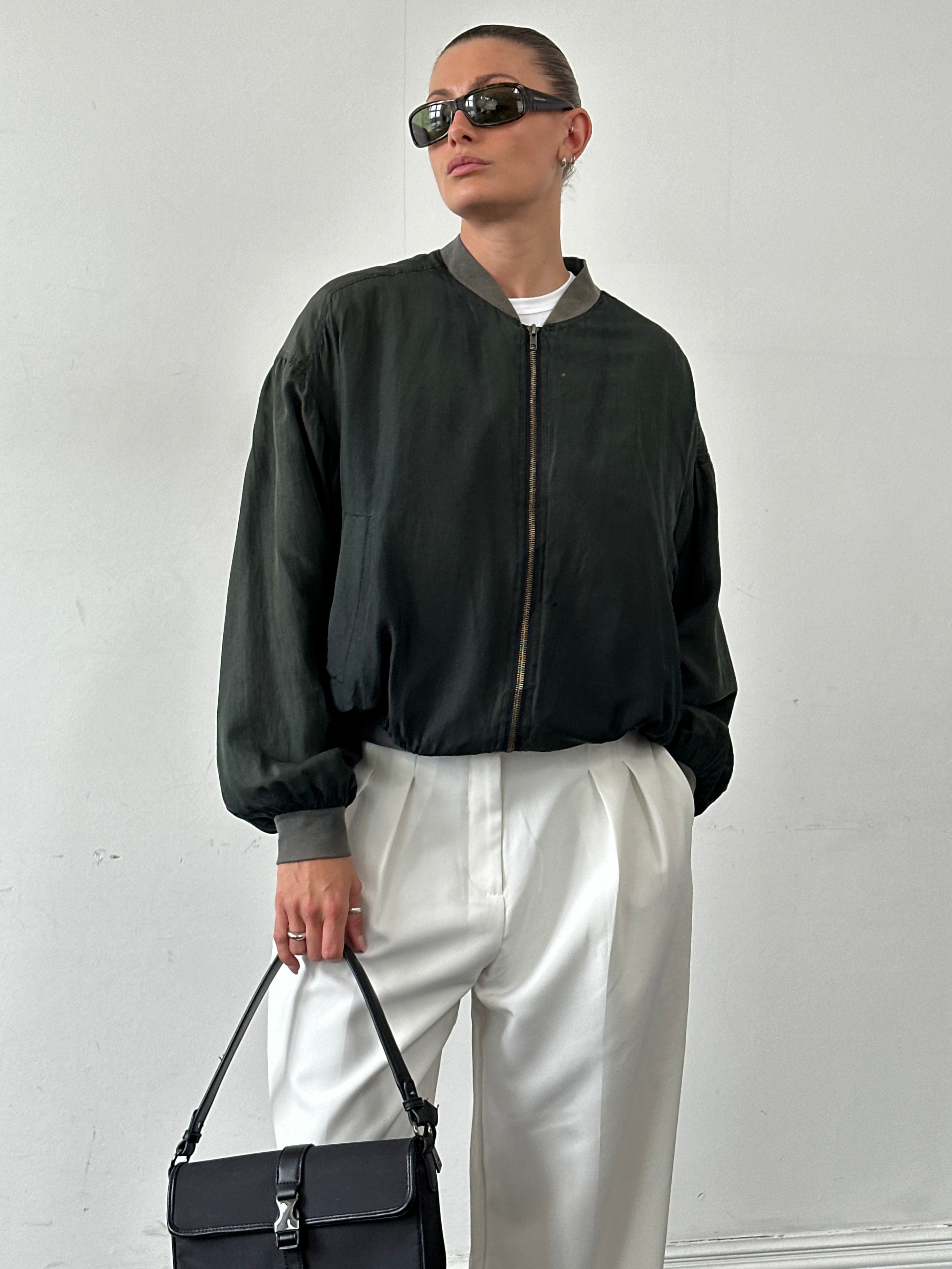 Vintage pure silk bomber jacket in size large with a classic design and smooth silk fabric, displayed on a hanger.