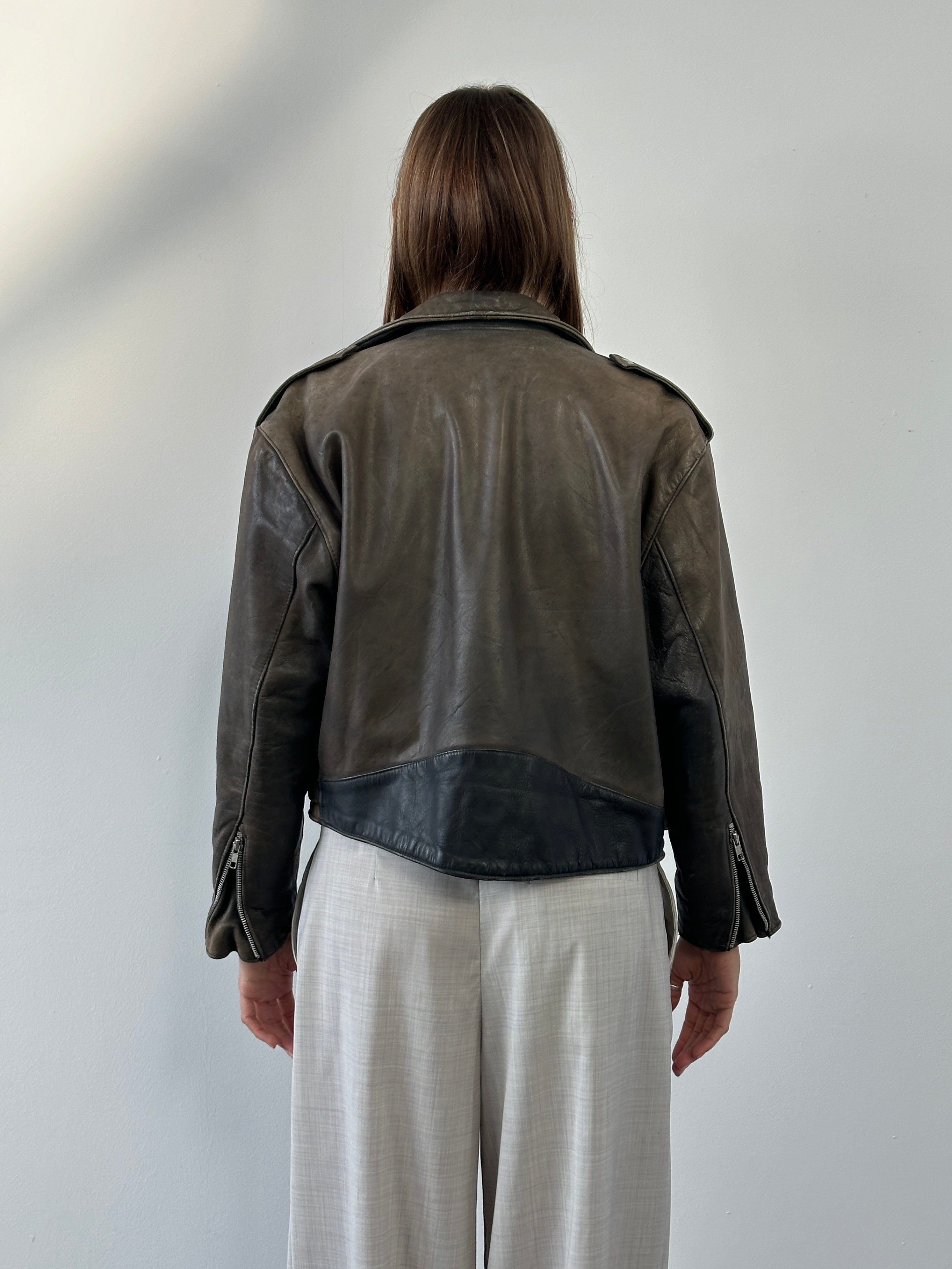 Vintage 1980s distressed leather biker jacket, size small, with rugged detailing and classic motorcycle style.