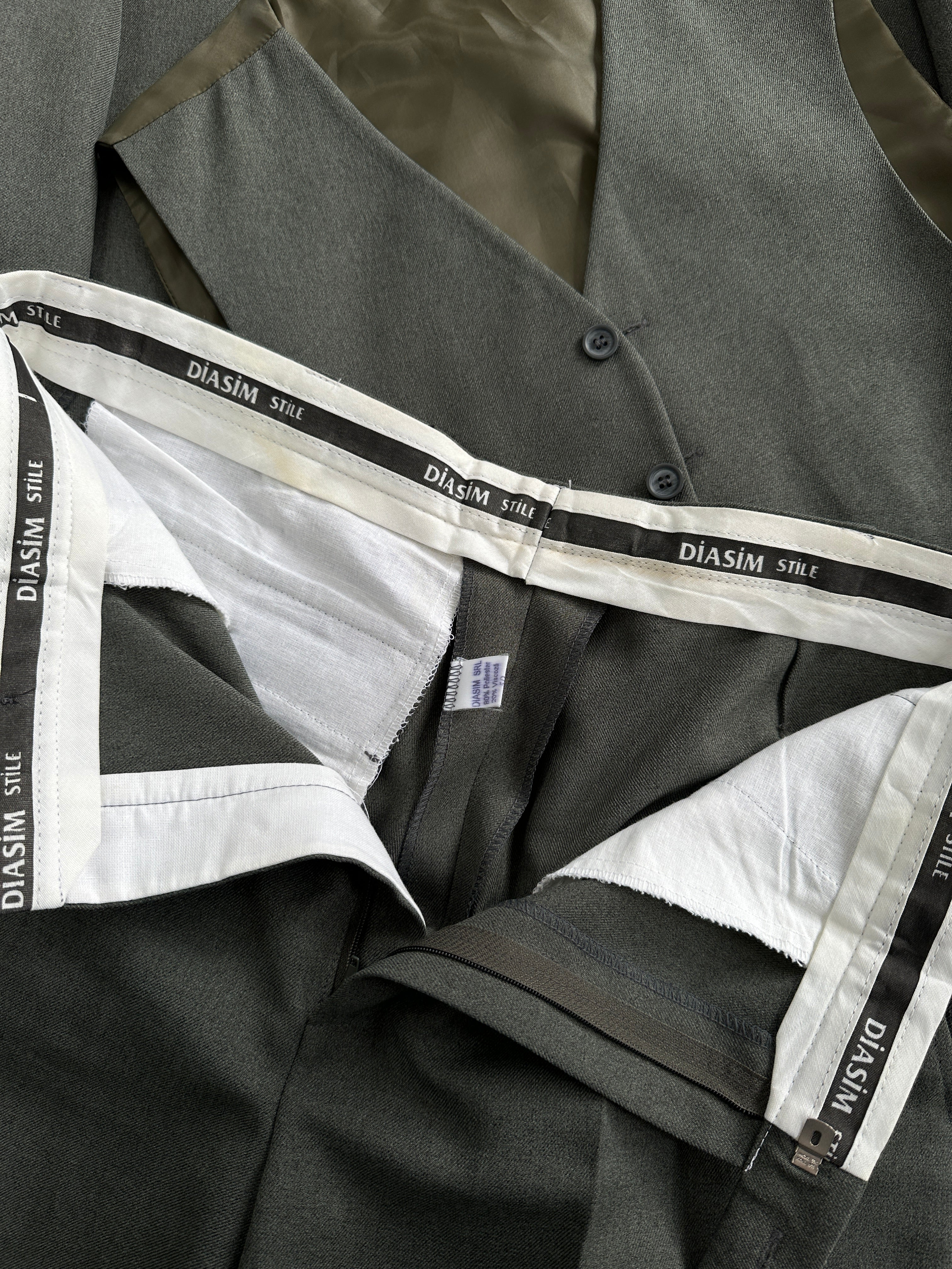 Vintage three-piece suit in 44R/W32 with jacket, vest, and trousers, featuring classic tailoring and neutral fabric.