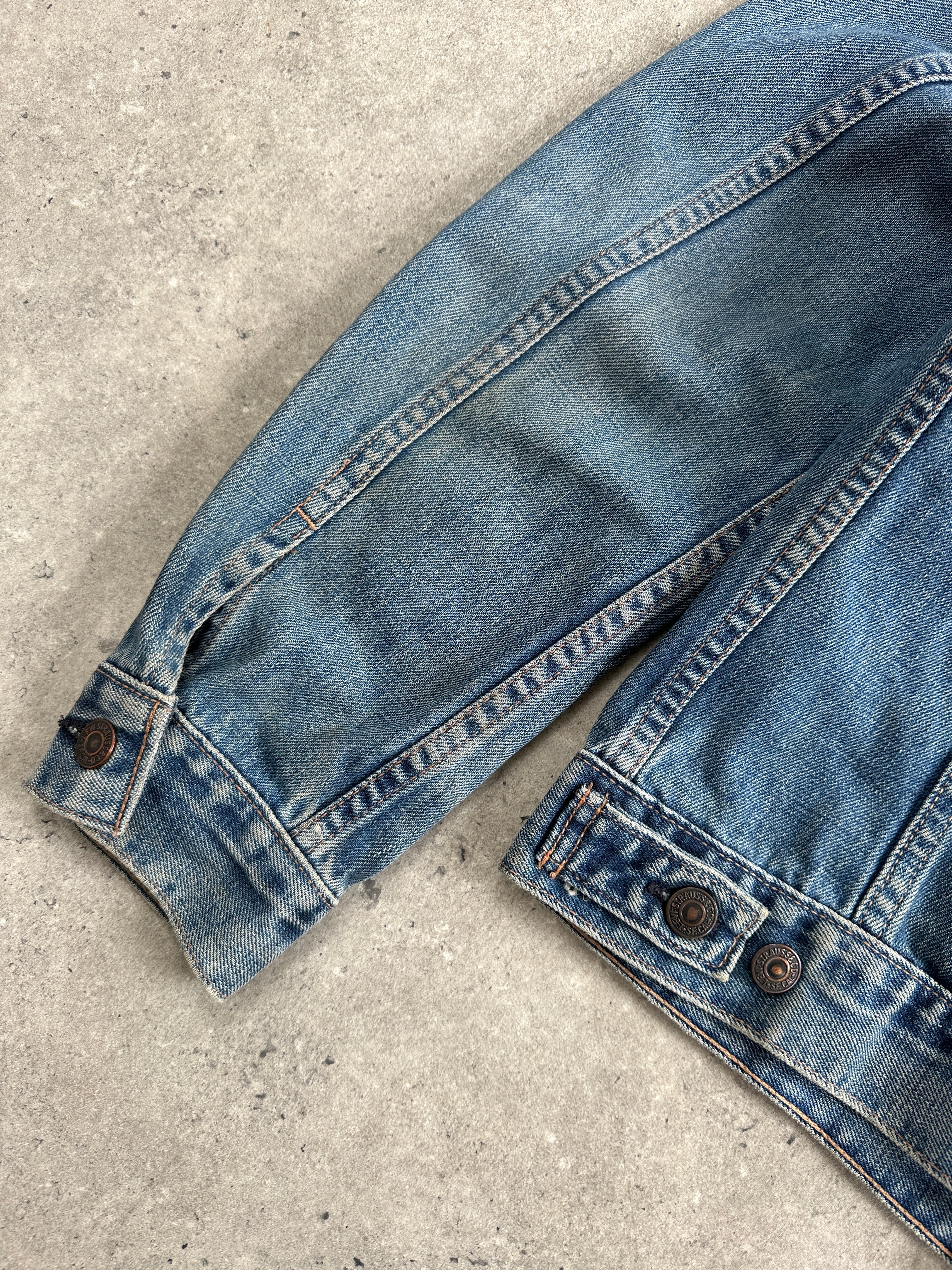 Levi’s 1990s faded denim jacket in medium size, showing classic distressed denim with a button-up front and collar detail.