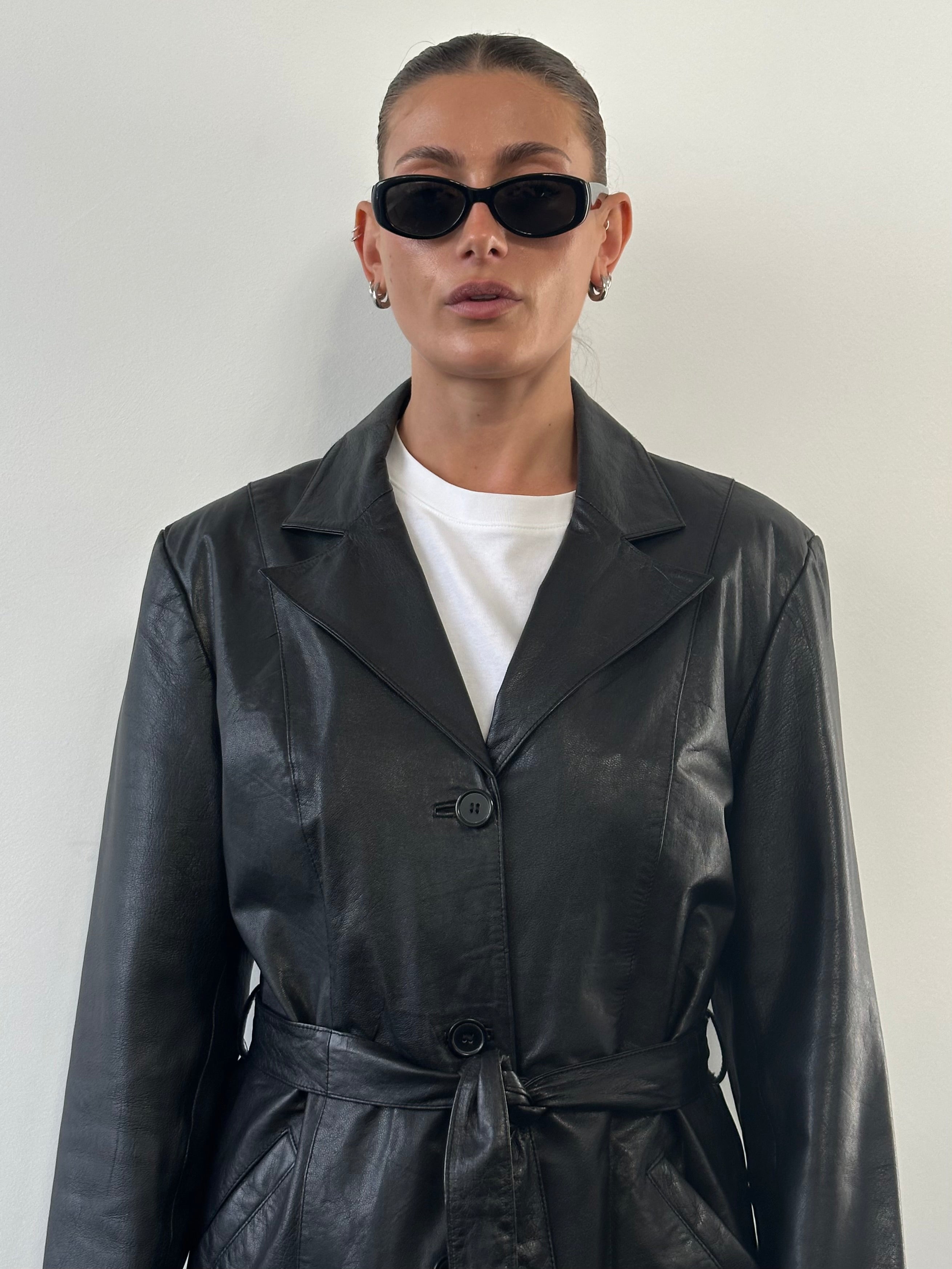 Vintage leather belted jacket in size M/L, featuring classic design and detailed stitching, displayed on a hanger.