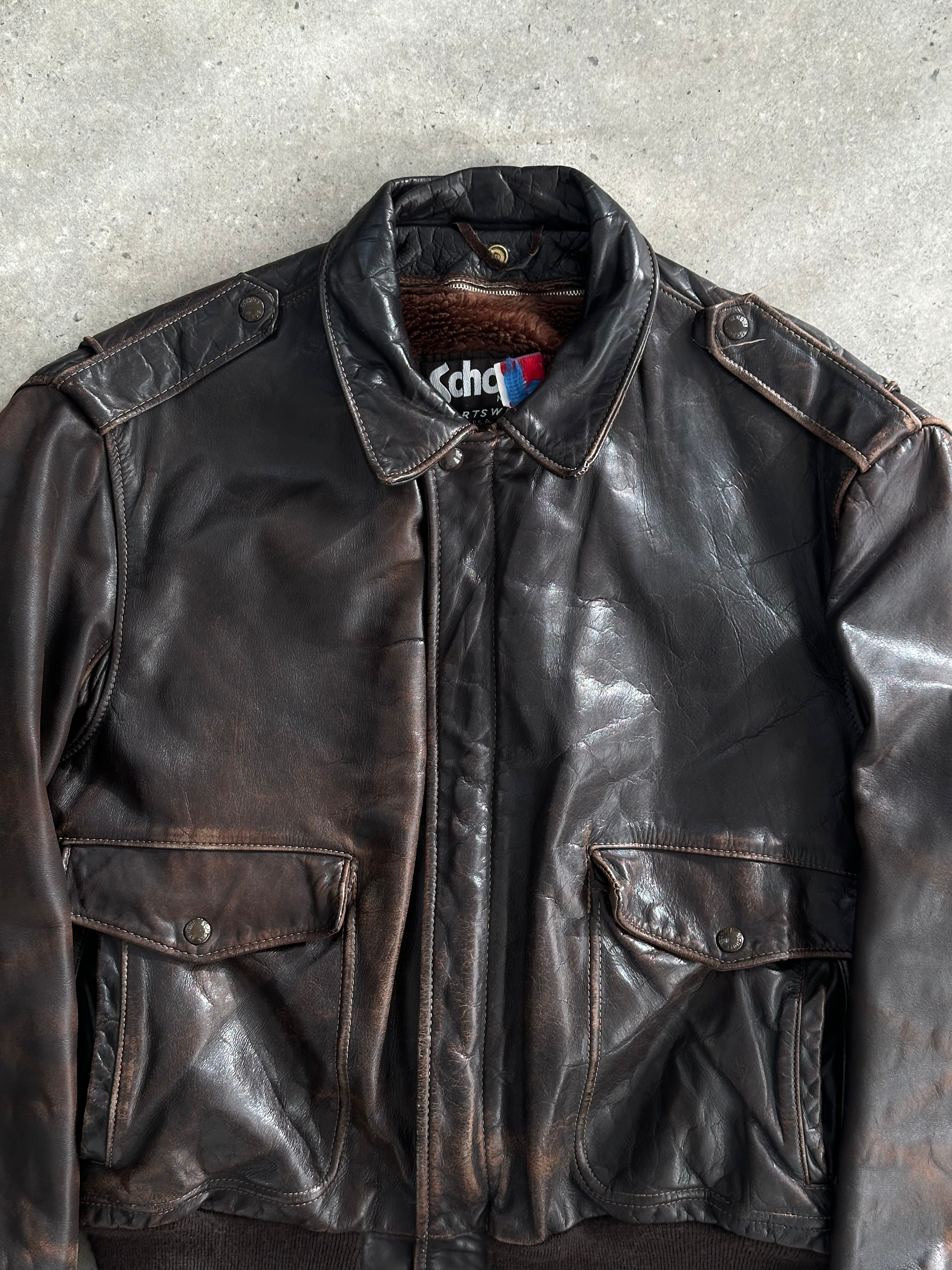 Schott NYC distressed leather bomber jacket in size L/XL with a worn-in look, featuring ribbed cuffs and collar, on a hanger.