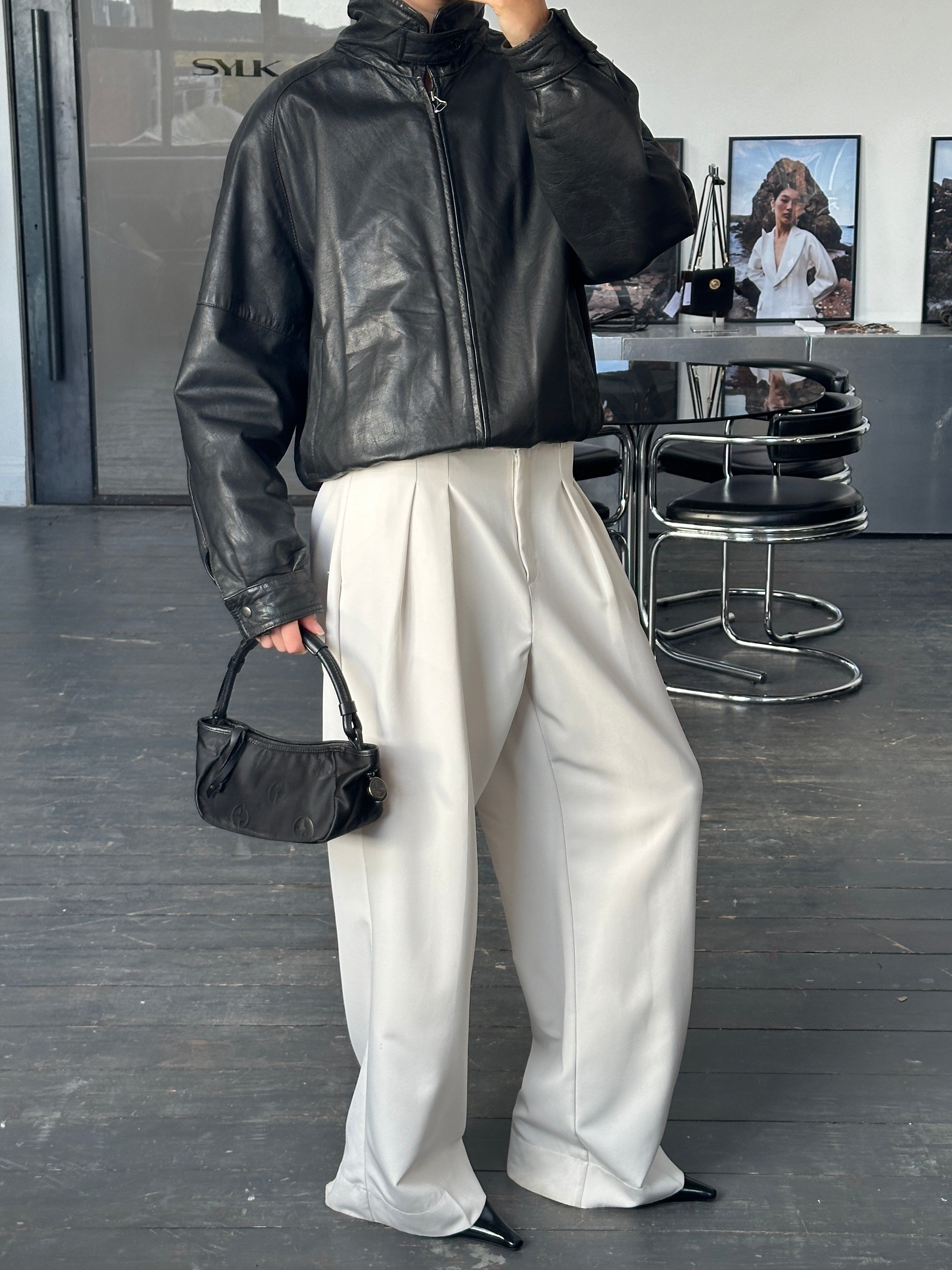 Vintage 1980s high neck leather bomber jacket in black, styled with classic design and visible zipper details.