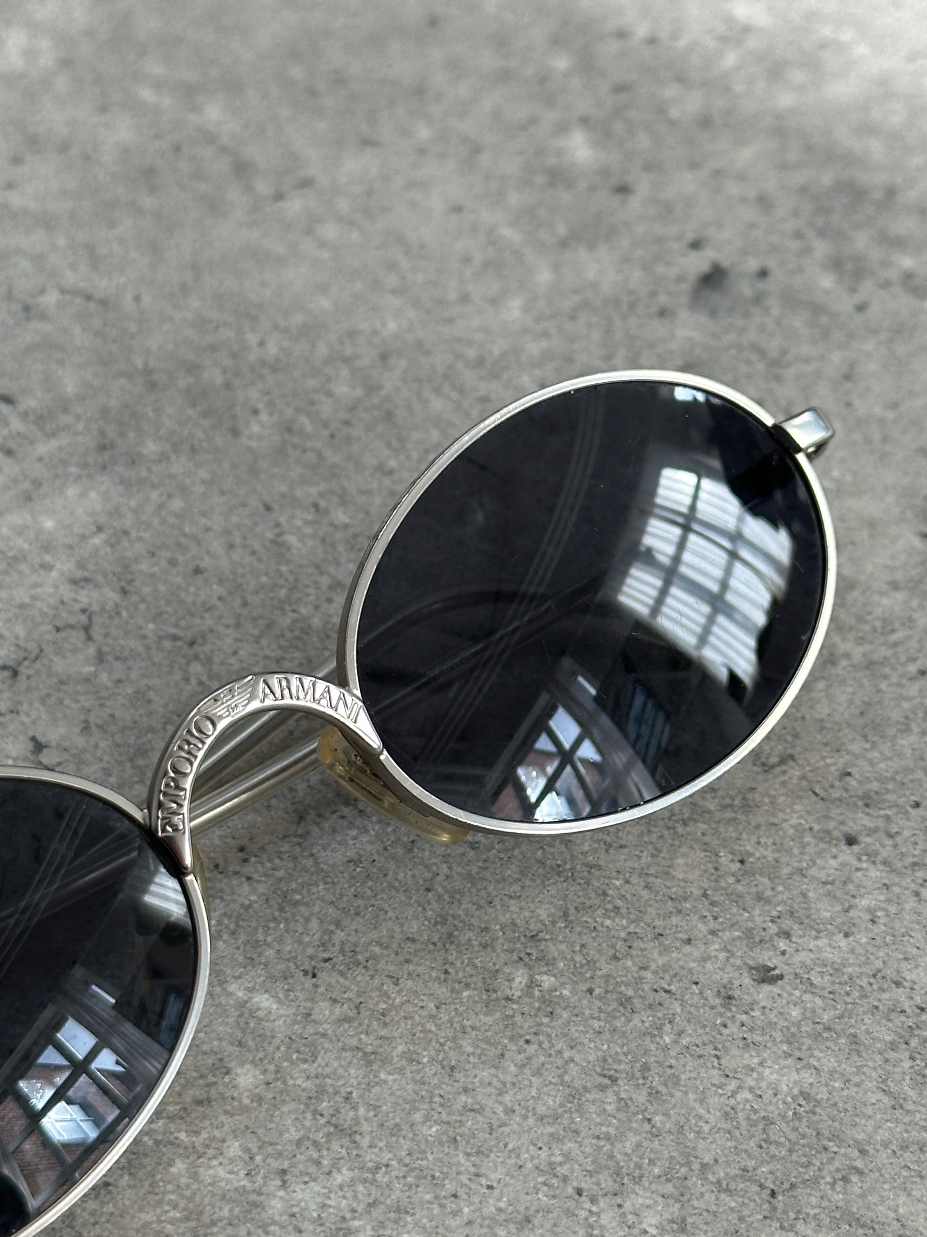 Emporio Armani metal oval sunglasses with sleek frame and dark tinted lenses for stylish sun protection.
