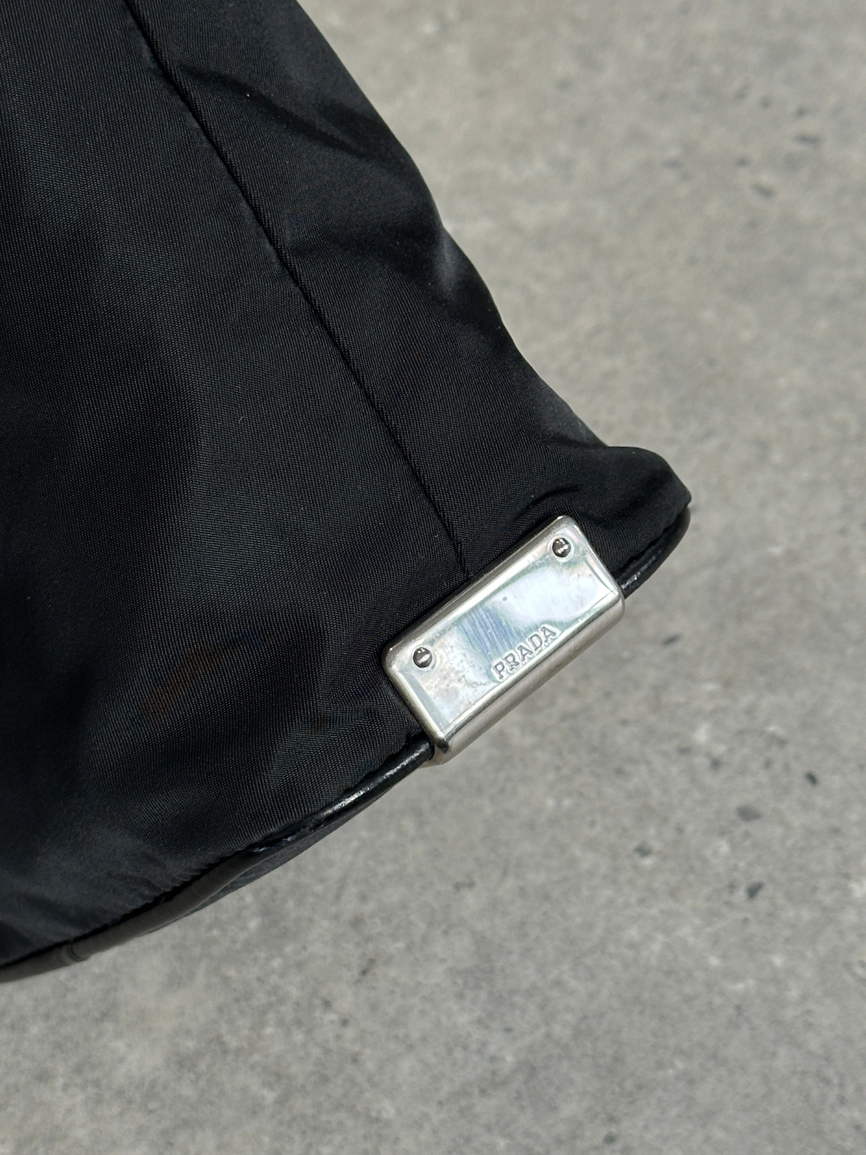 Prada nylon shoulder bag with chrome logo hardware, featuring a sleek design and adjustable strap for versatile carrying.