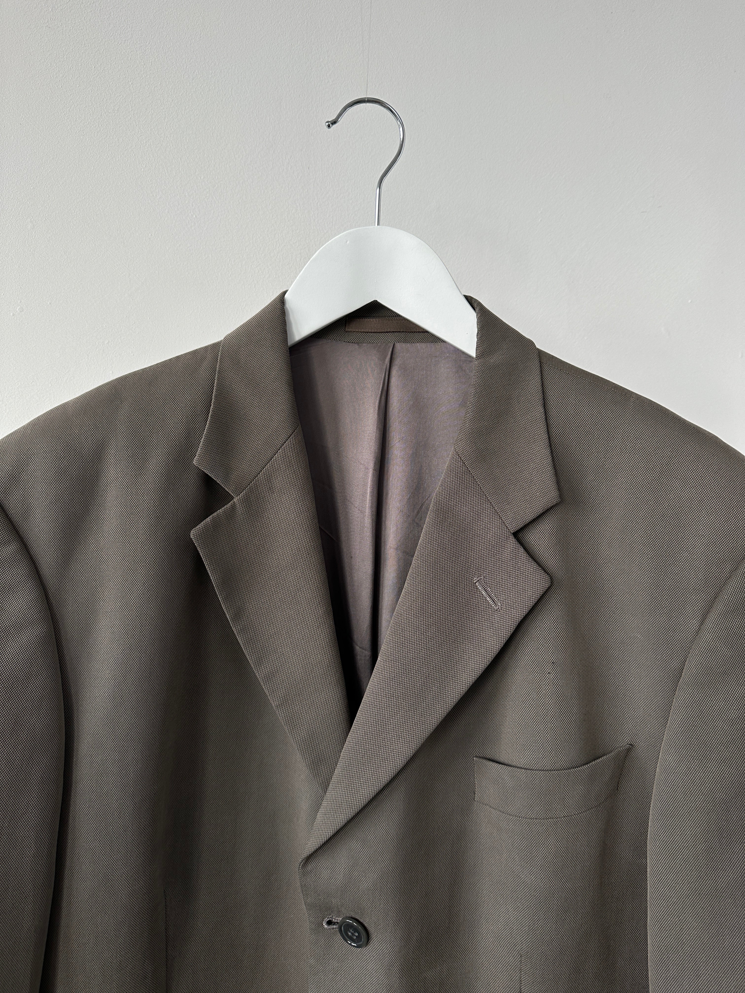 Vintage relaxed single-breasted blazer in size L/XL, shown hanging on a wooden hanger with classic lapels and tailored fit.