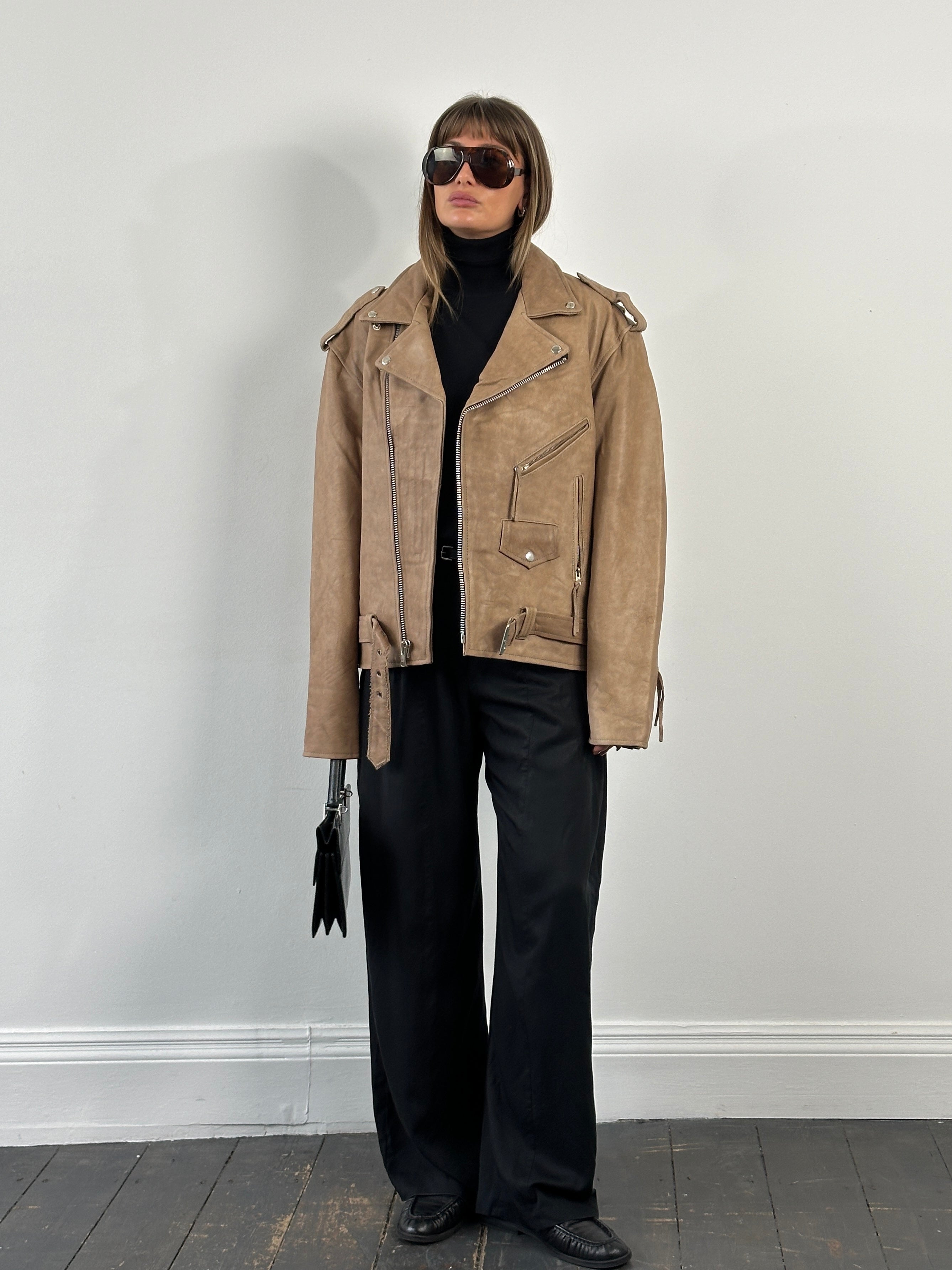 Vintage 1990s leather biker jacket in XL with classic distressed leather and silver hardware, displayed on a hanger.