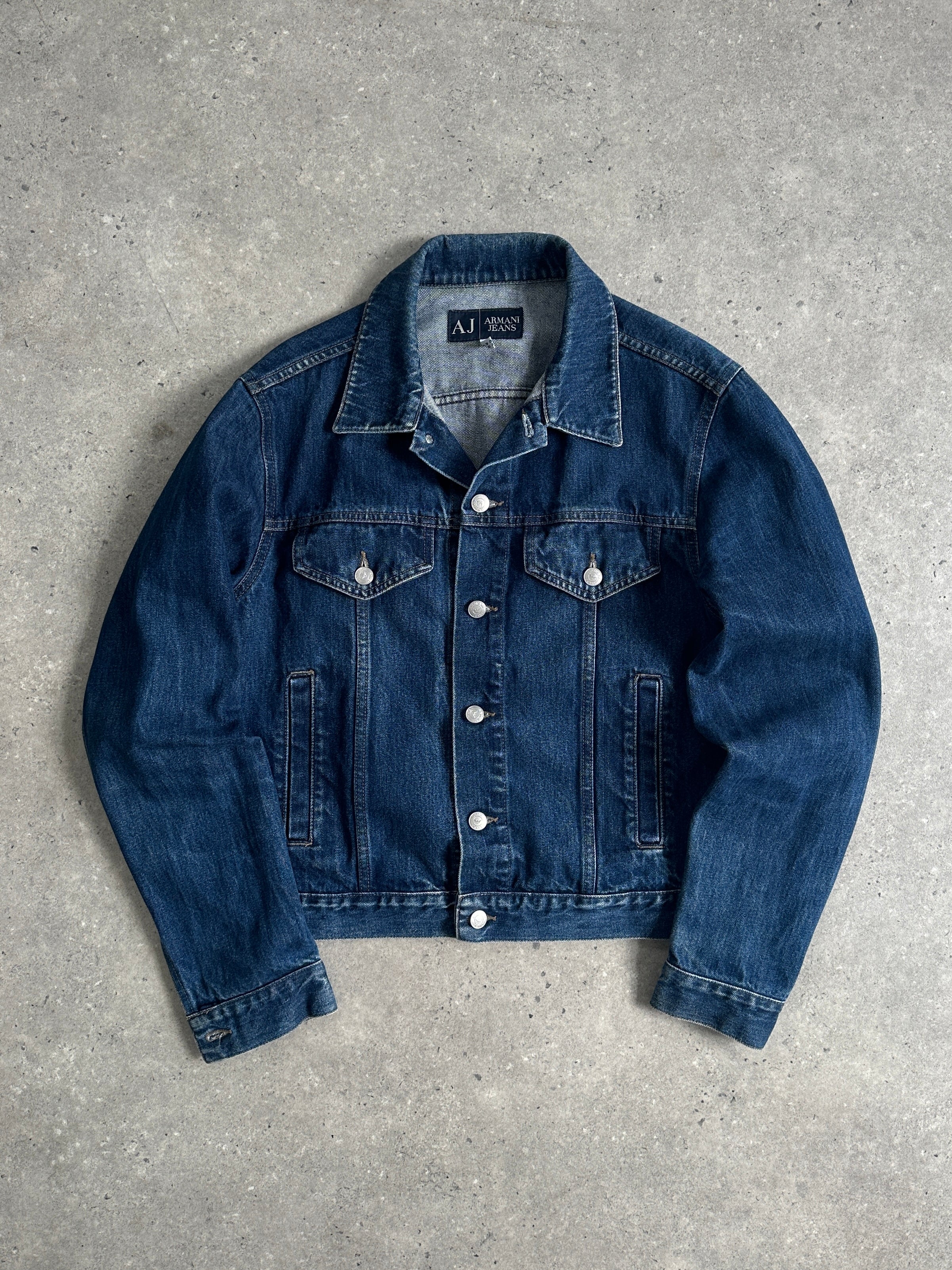 Armani Jeans mid wash denim jacket in size S/M displayed on a hanger, featuring classic collar and button-front design.