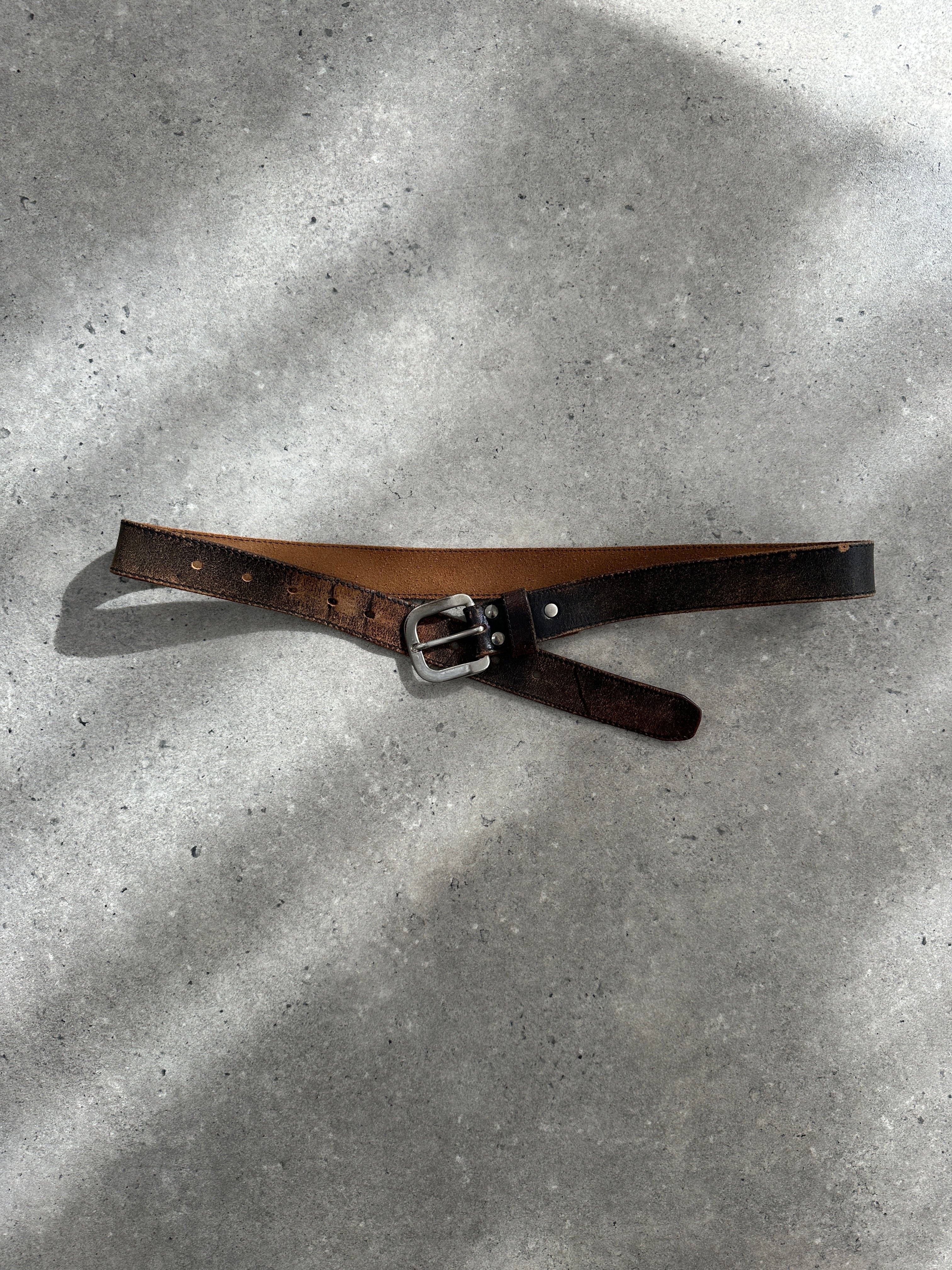 Vintage 1980s distressed leather belt with metal buckle, adjustable W27-35, showcasing a rugged, worn-in leather finish.