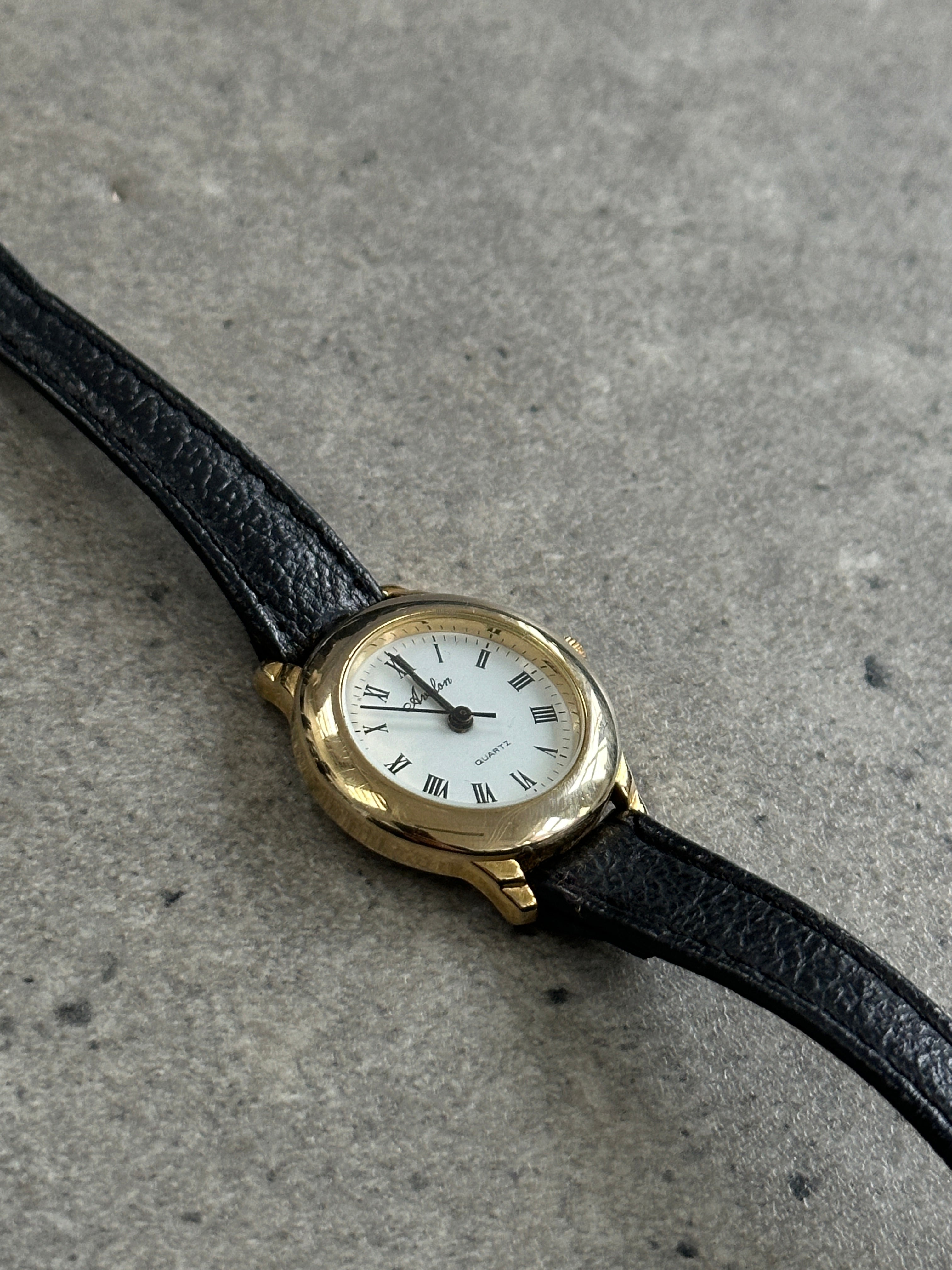 Vintage 1990s gold tone round quartz watch with classic design and metal band, showcasing a vintage timepiece style.