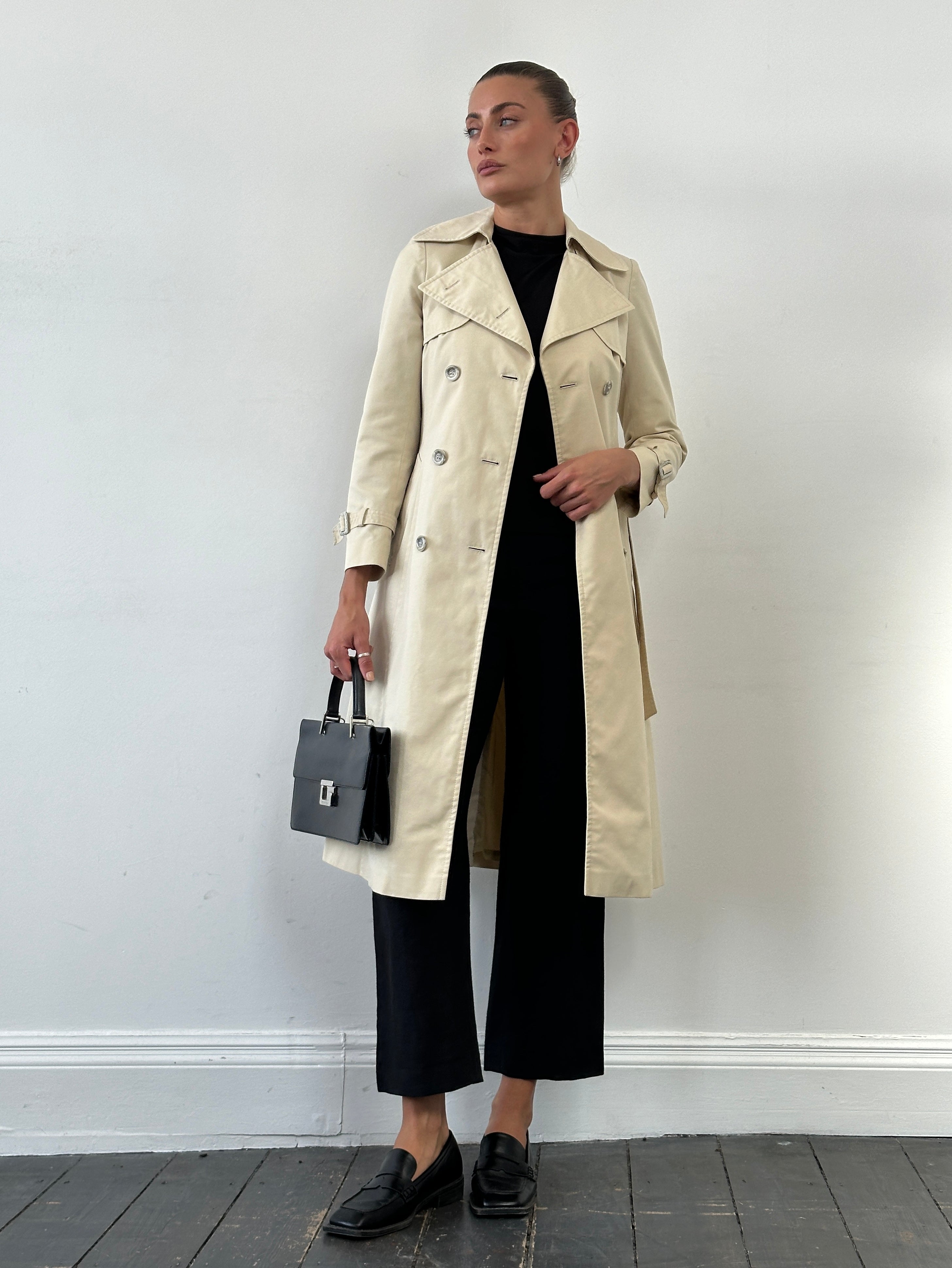 Vintage 1980s cotton double-breasted belted trench coat in beige, featuring classic design and XS size, displayed on a hanger.