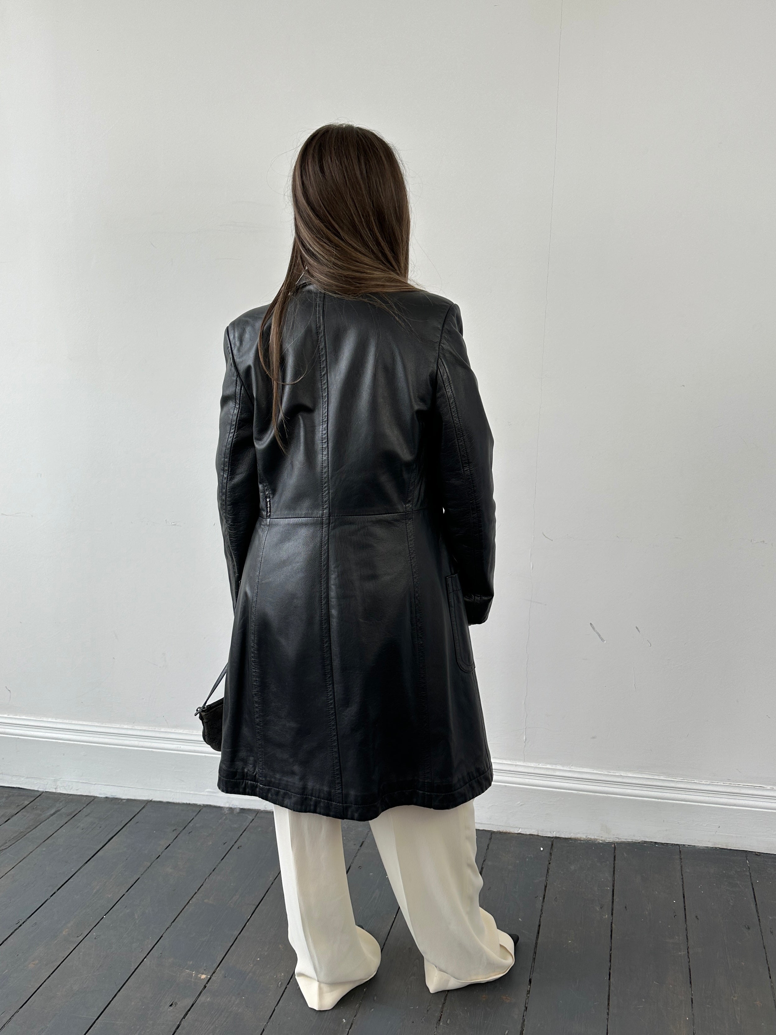 Armani leather trench coat in XS displayed on a hanger, showcasing sleek design and high-quality black leather material.