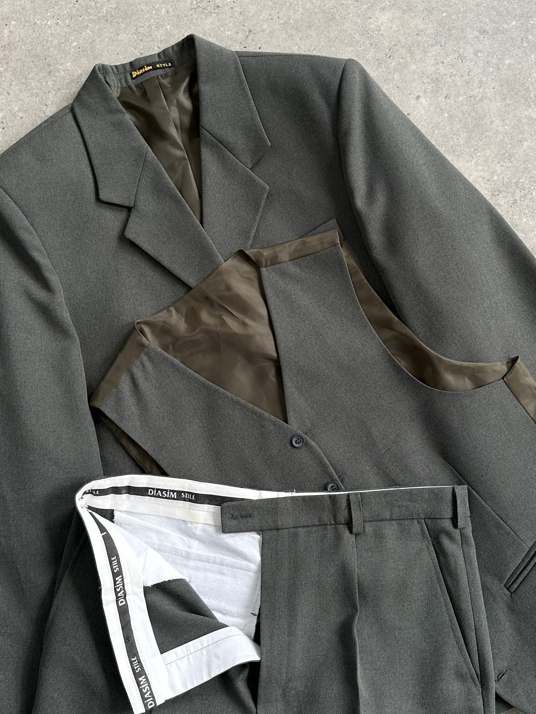 Vintage three-piece men's suit in size 44R/W32, featuring a tailored blazer, vest, and matching trousers, displayed on a hanger.